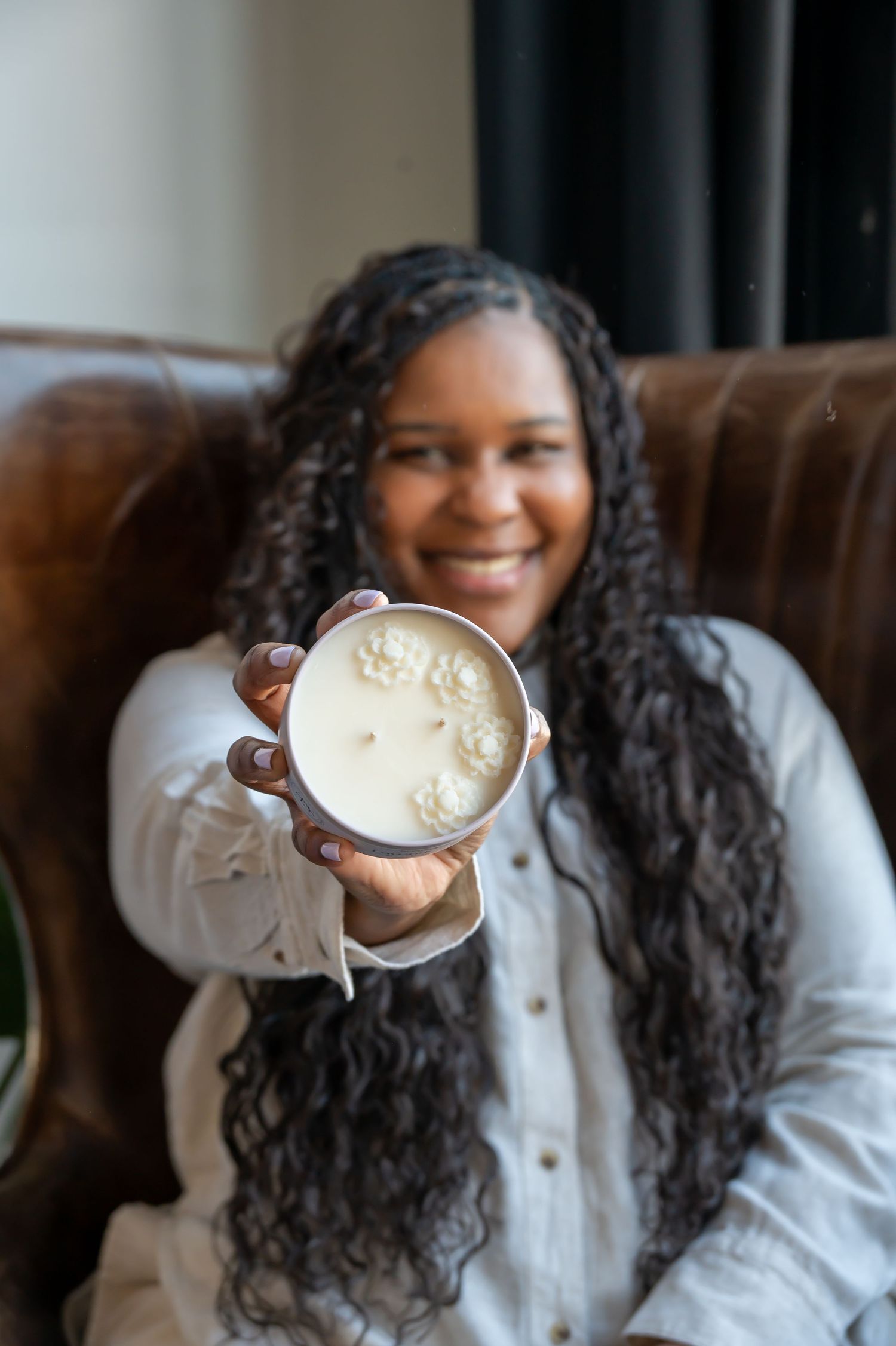 Person holding a candle while relaxing on a brown leather couch.