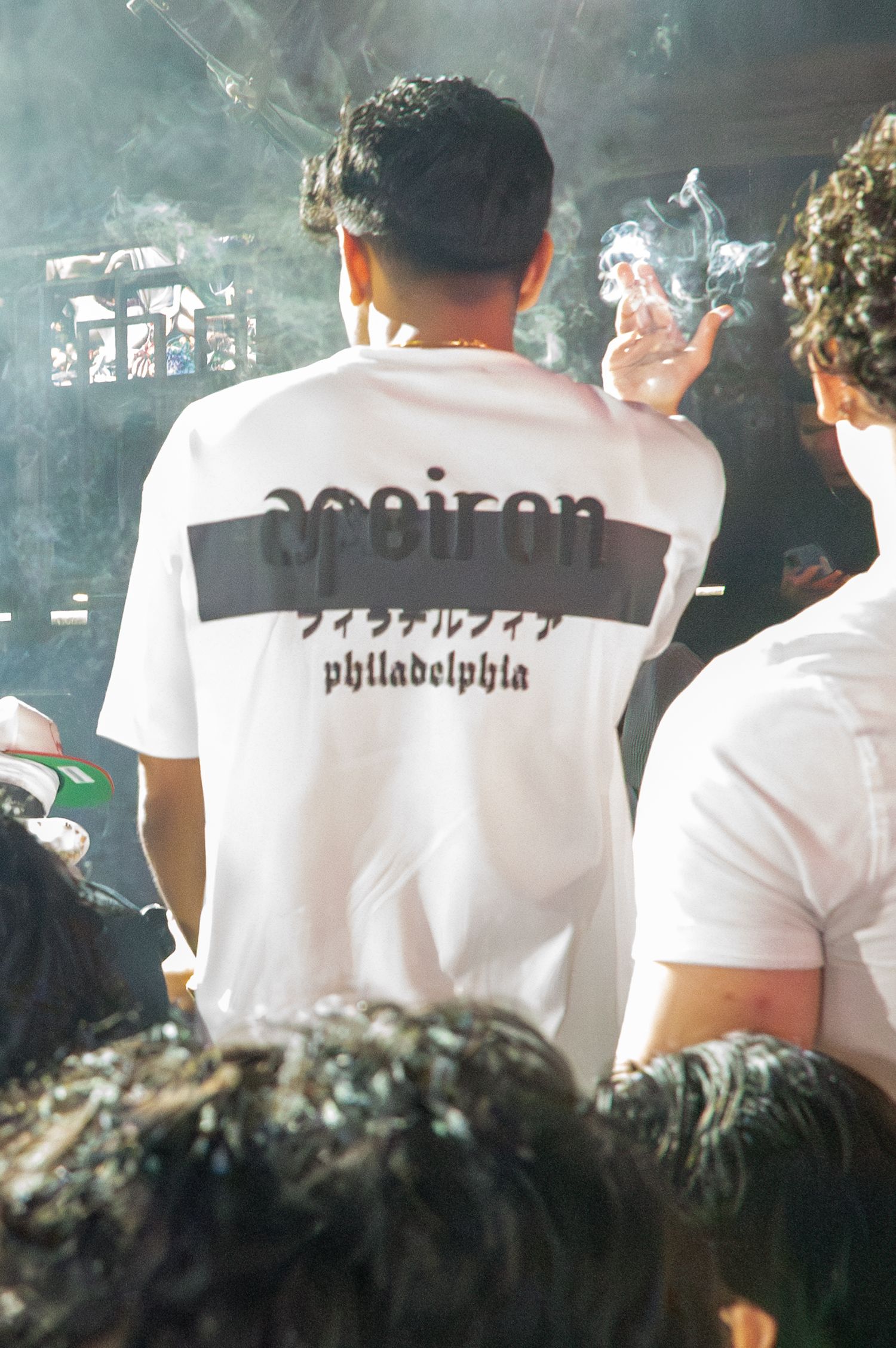 Row of people wearing white t-shirts with text in a smoky atmosphere.