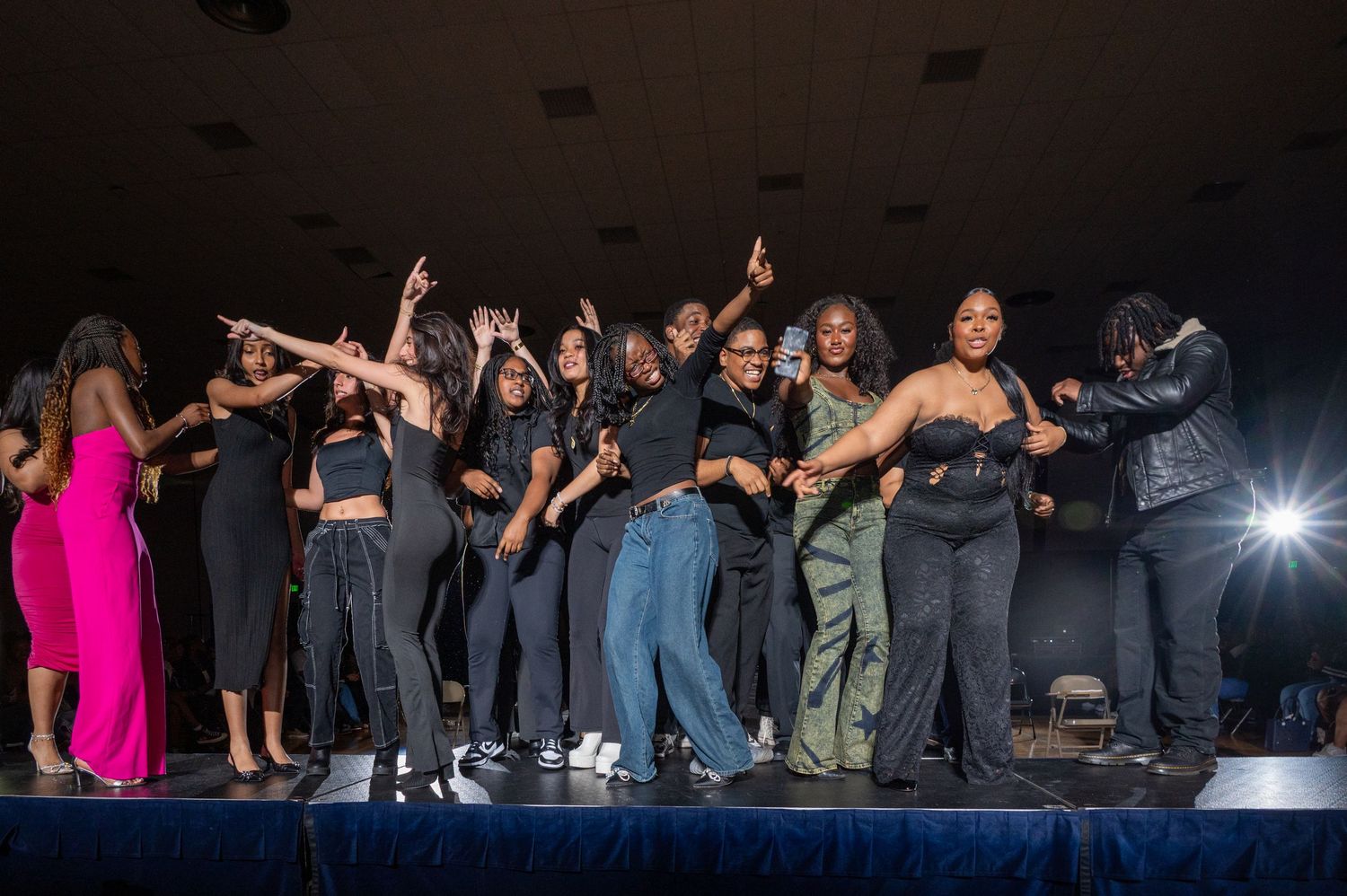 Audience members raise their arms in solidarity during a theatrical performance.
