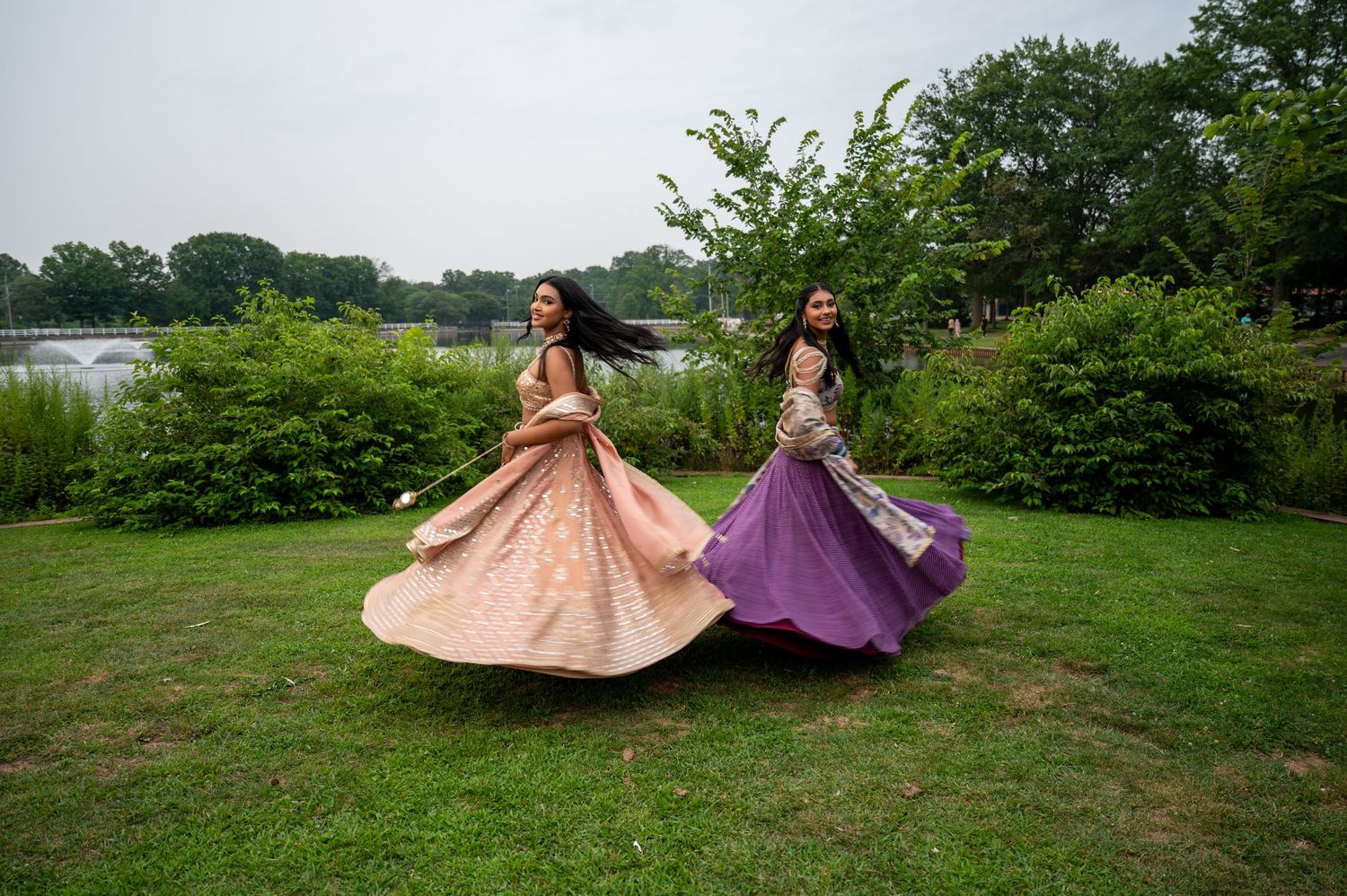 Wide shot of two models in formal wear posing dramatically on grassy field.