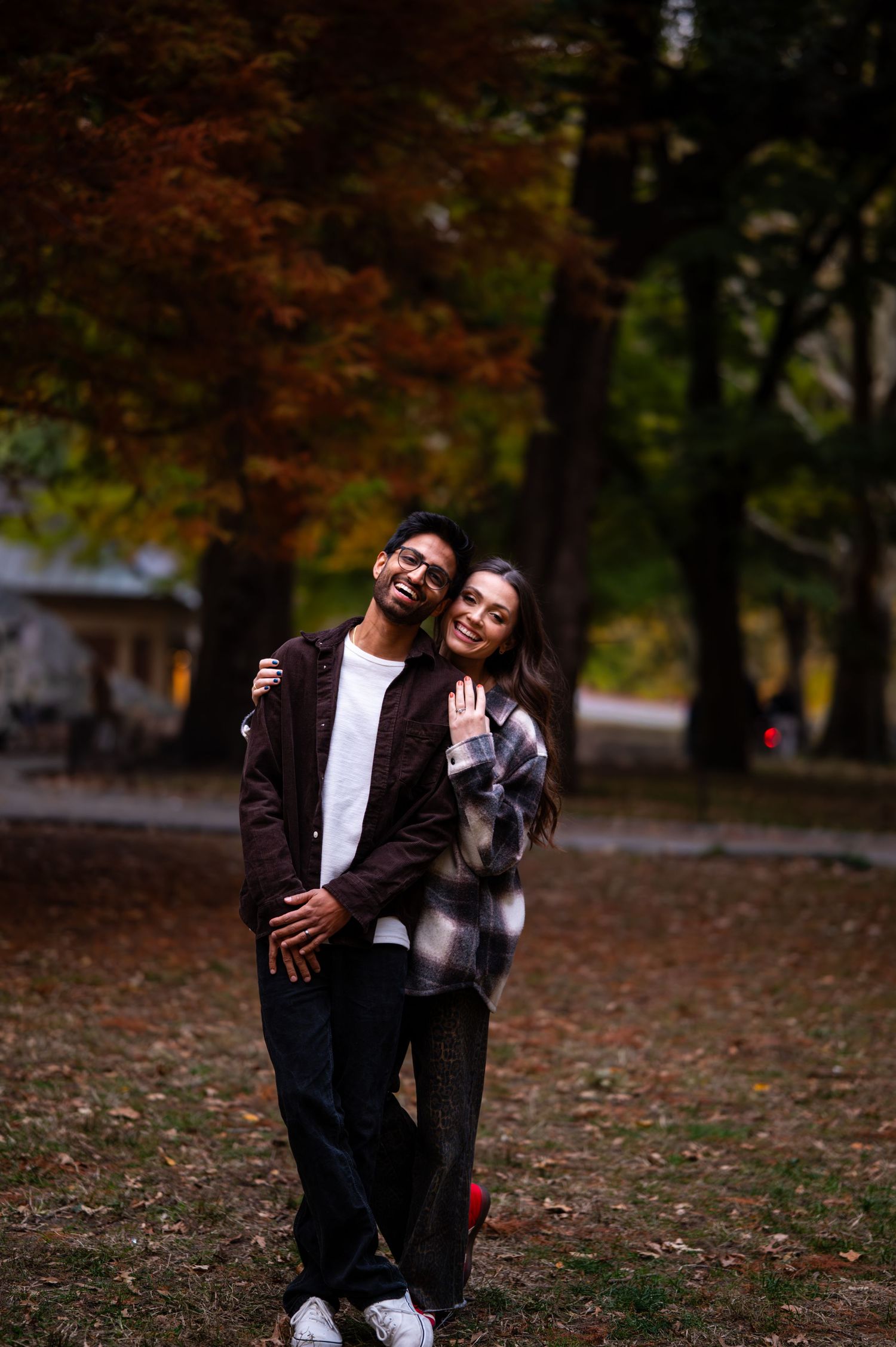 A joyful moment captured between two people in a park during autumn.