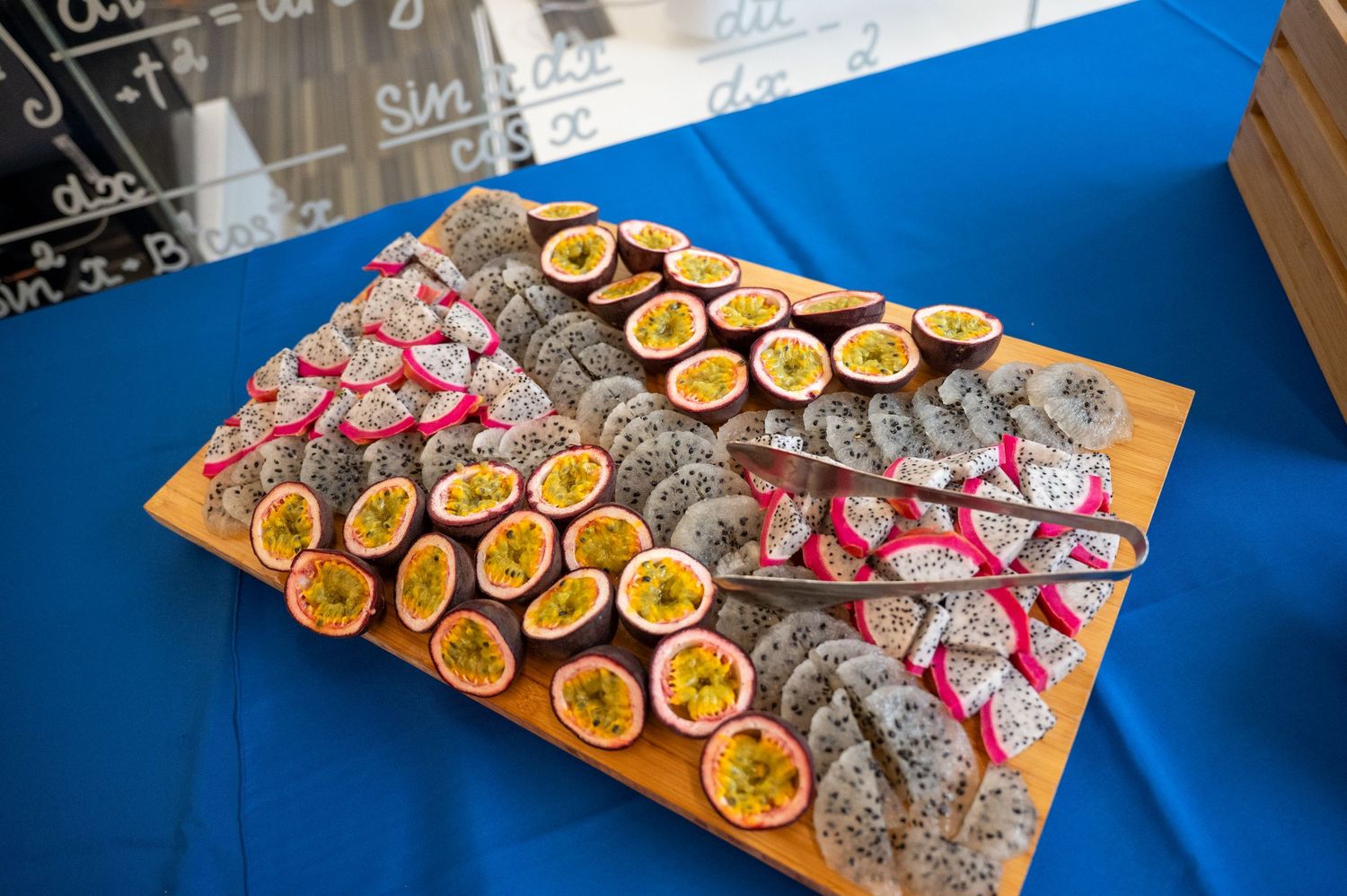 Catering display featuring sliced citrus fruits and appetizers on blue tablecloth.
