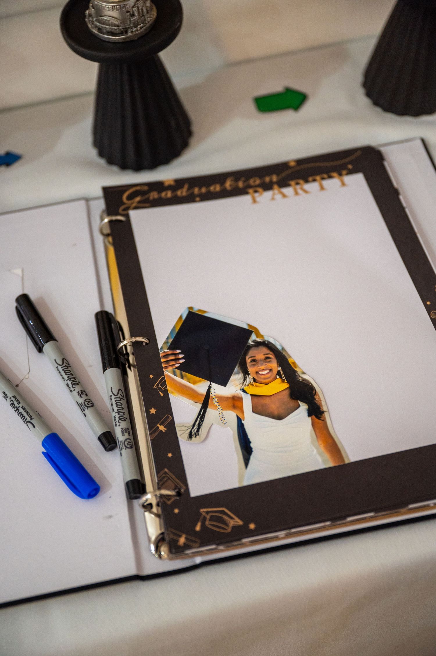 Graduation guest book with pens and decorative elements on white table.