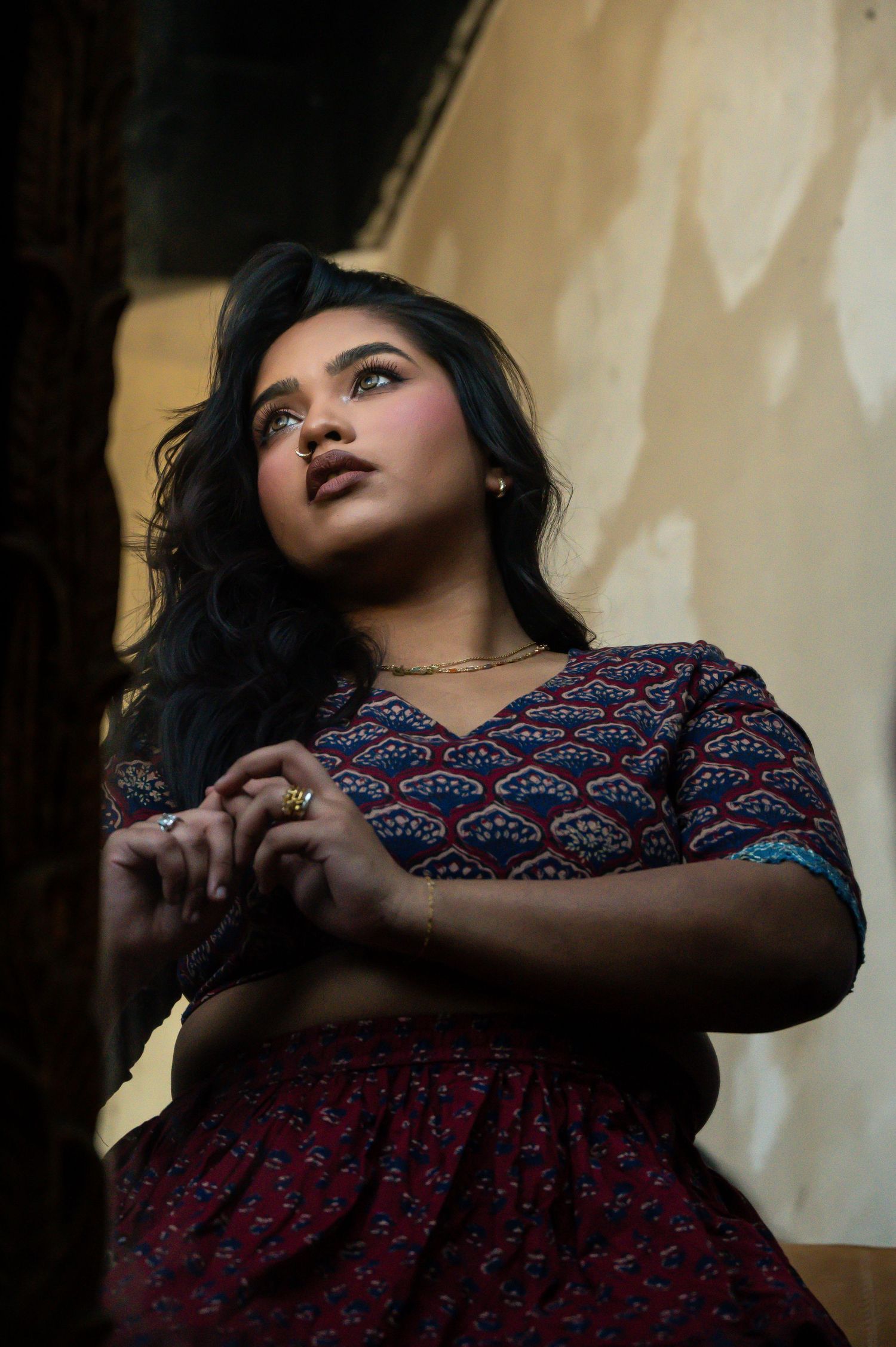 Artistic portrait series in moody lighting featuring a person in a patterned dress against a light background.