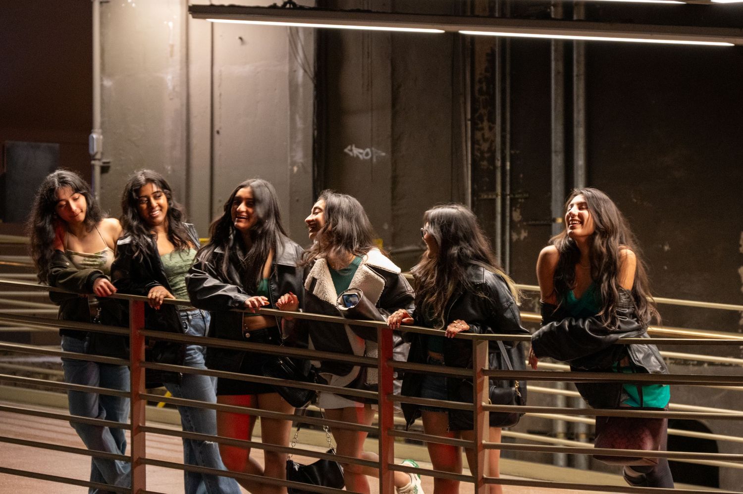 Group sitting together on dark benches in dimly lit space.