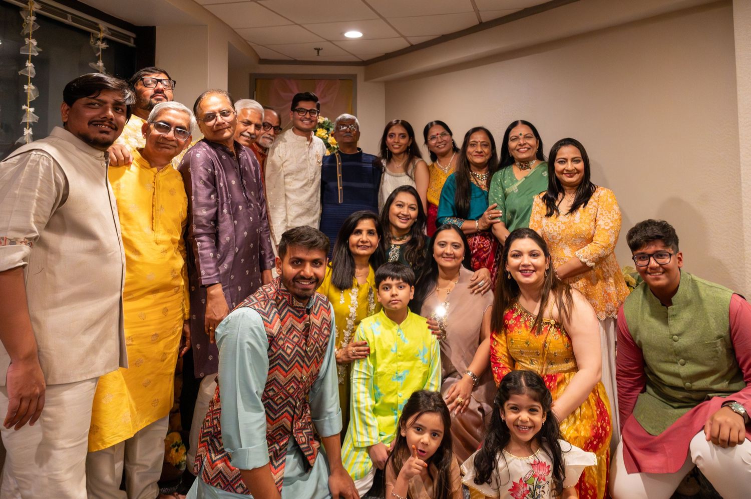 A group of people in colorful traditional Indian attire gather together for a festive celebration photo.
