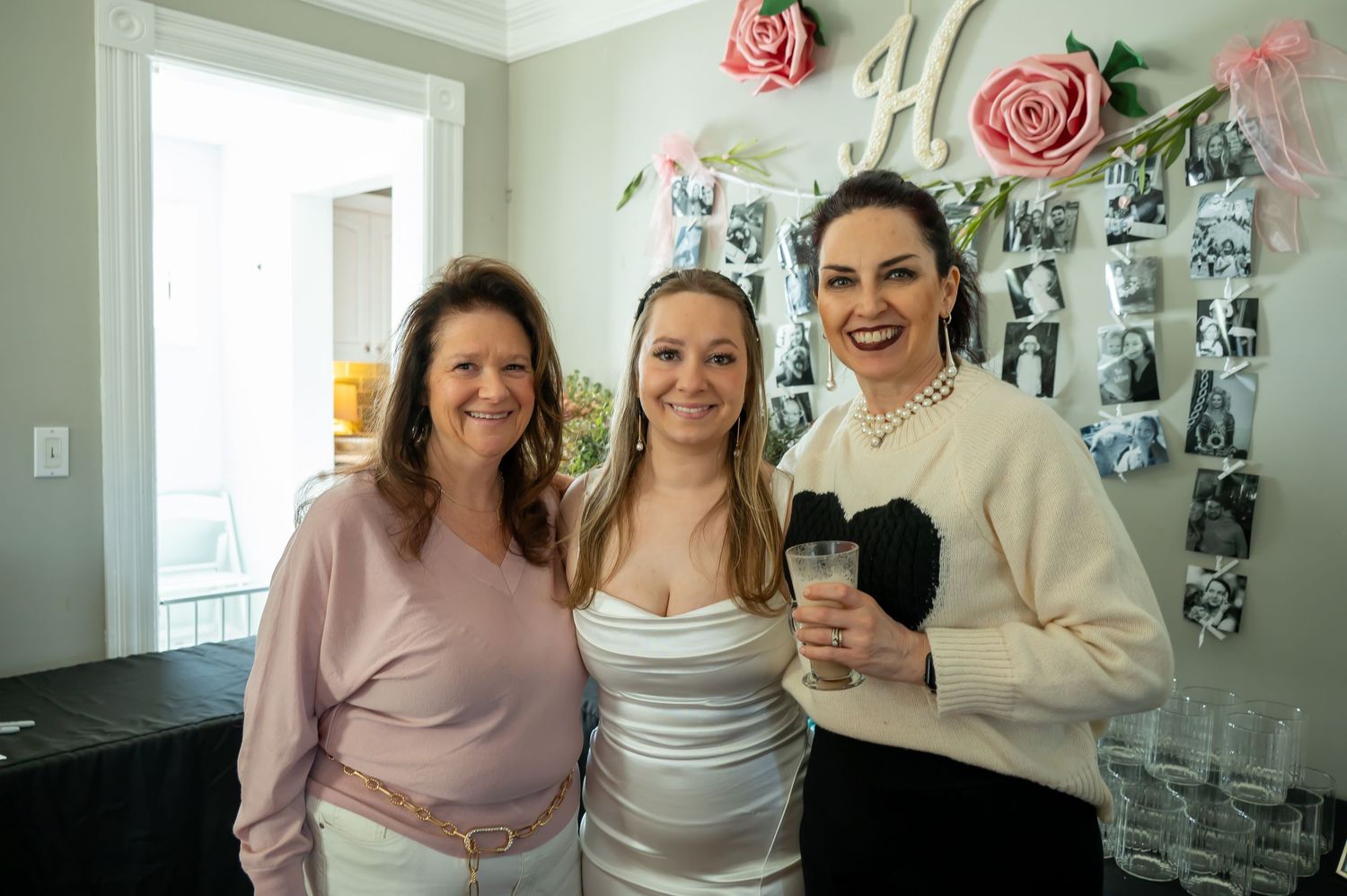 A group celebrating in a room decorated with pink flowers and balloons.
