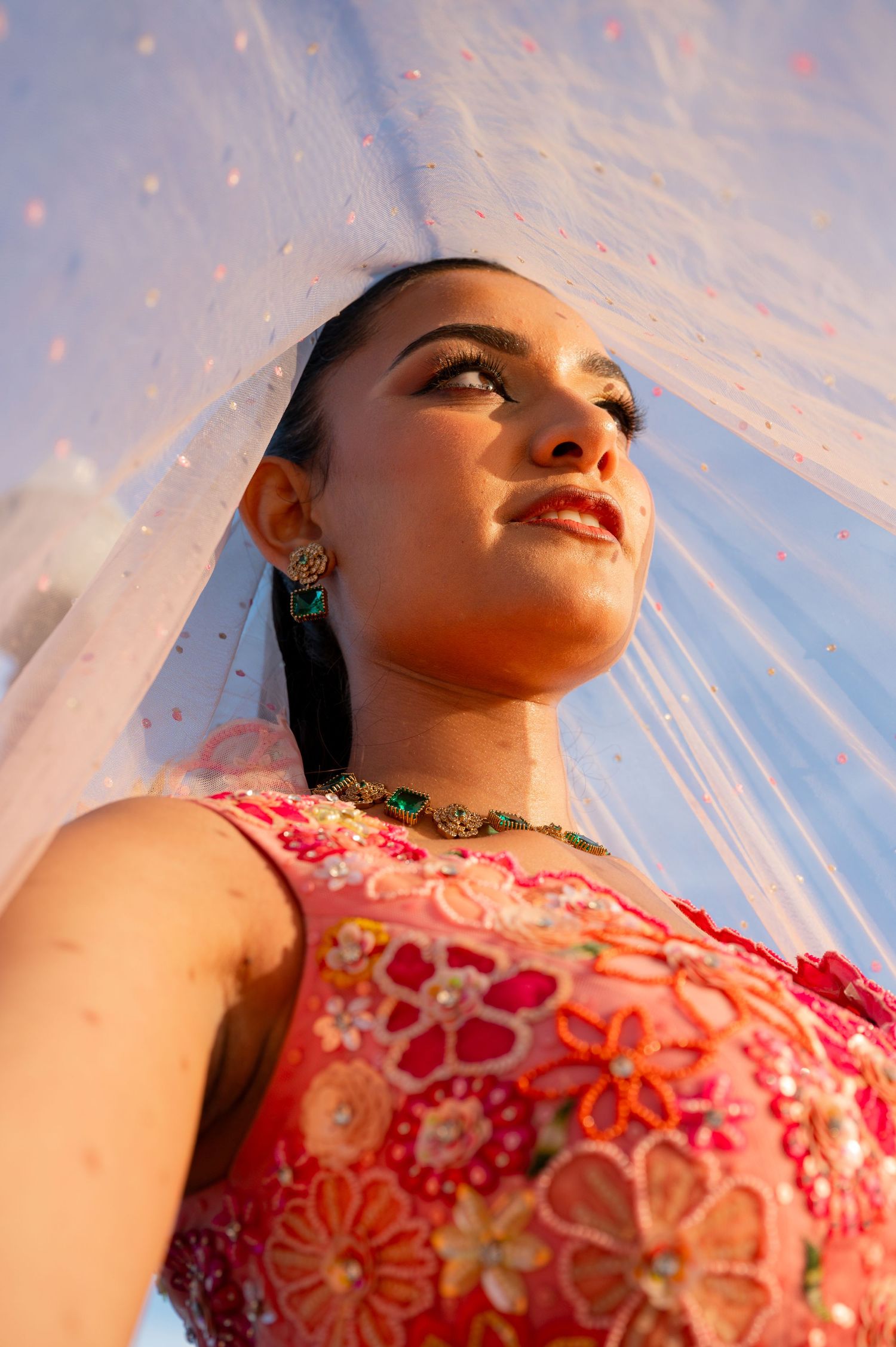 Close-up shot of woman in pink embellished dress during golden hour.