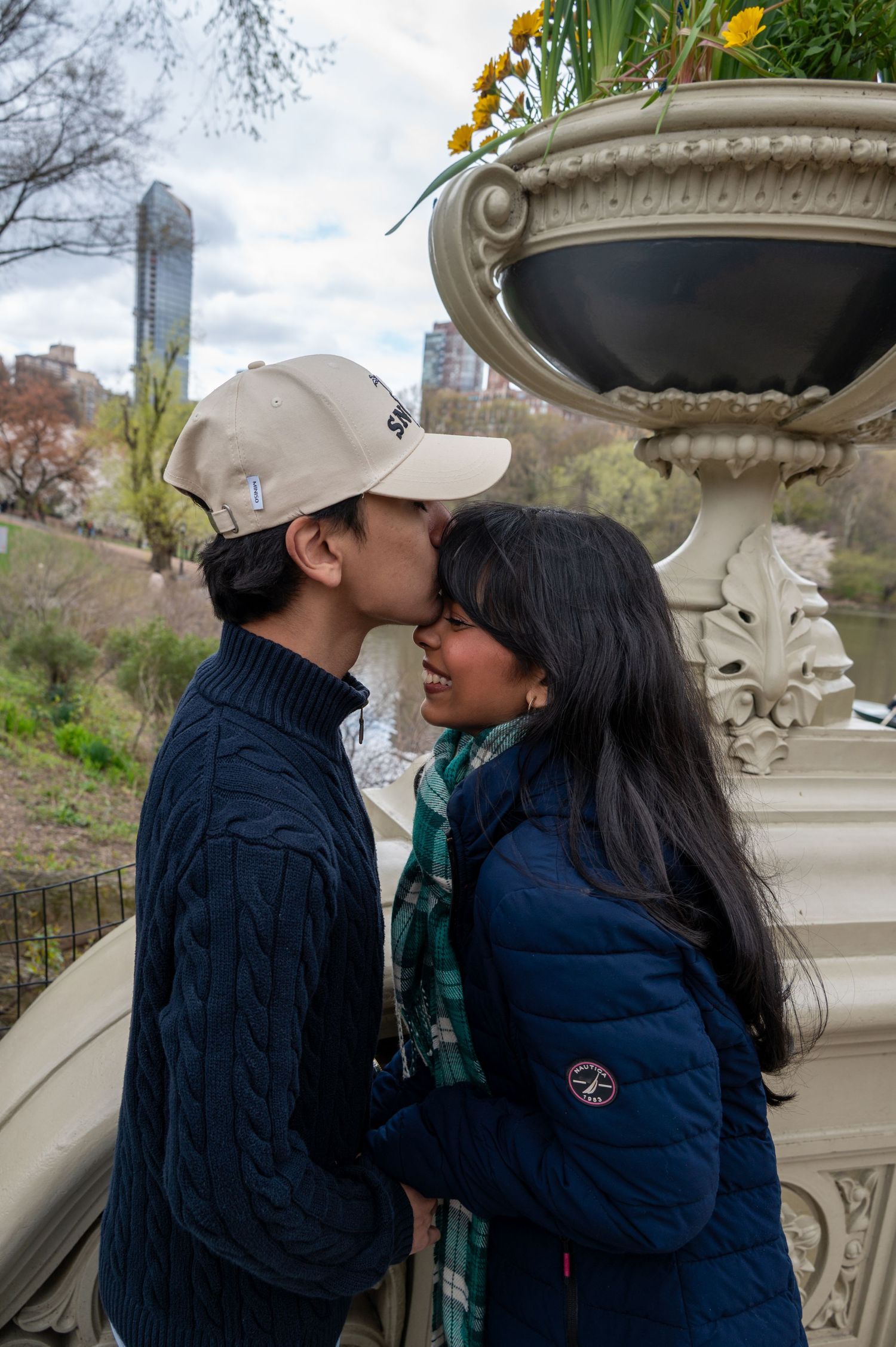 A romantic moment shared between a couple near an ornate stone urn in Central Park.