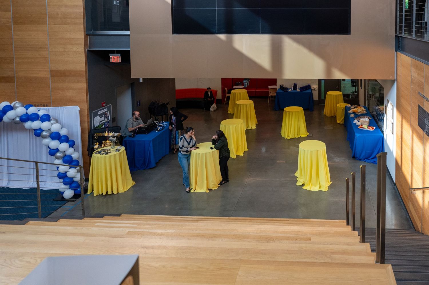 Event space with yellow cocktail tables and blue balloon decorations.