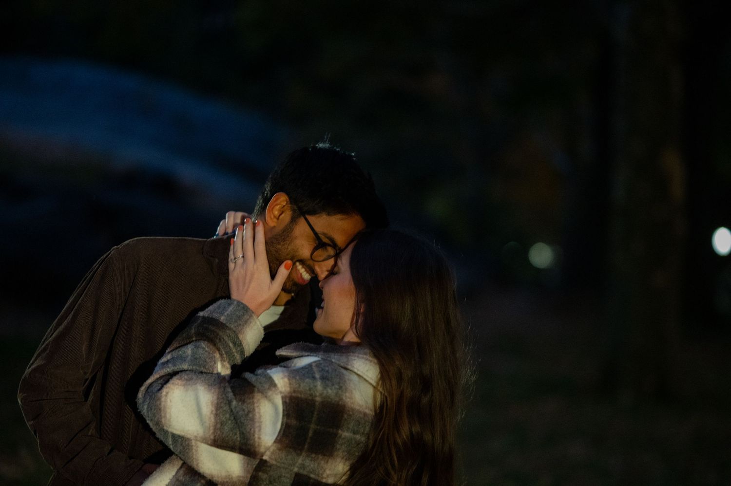 An intimate nighttime portrait with soft bokeh lights in the background.