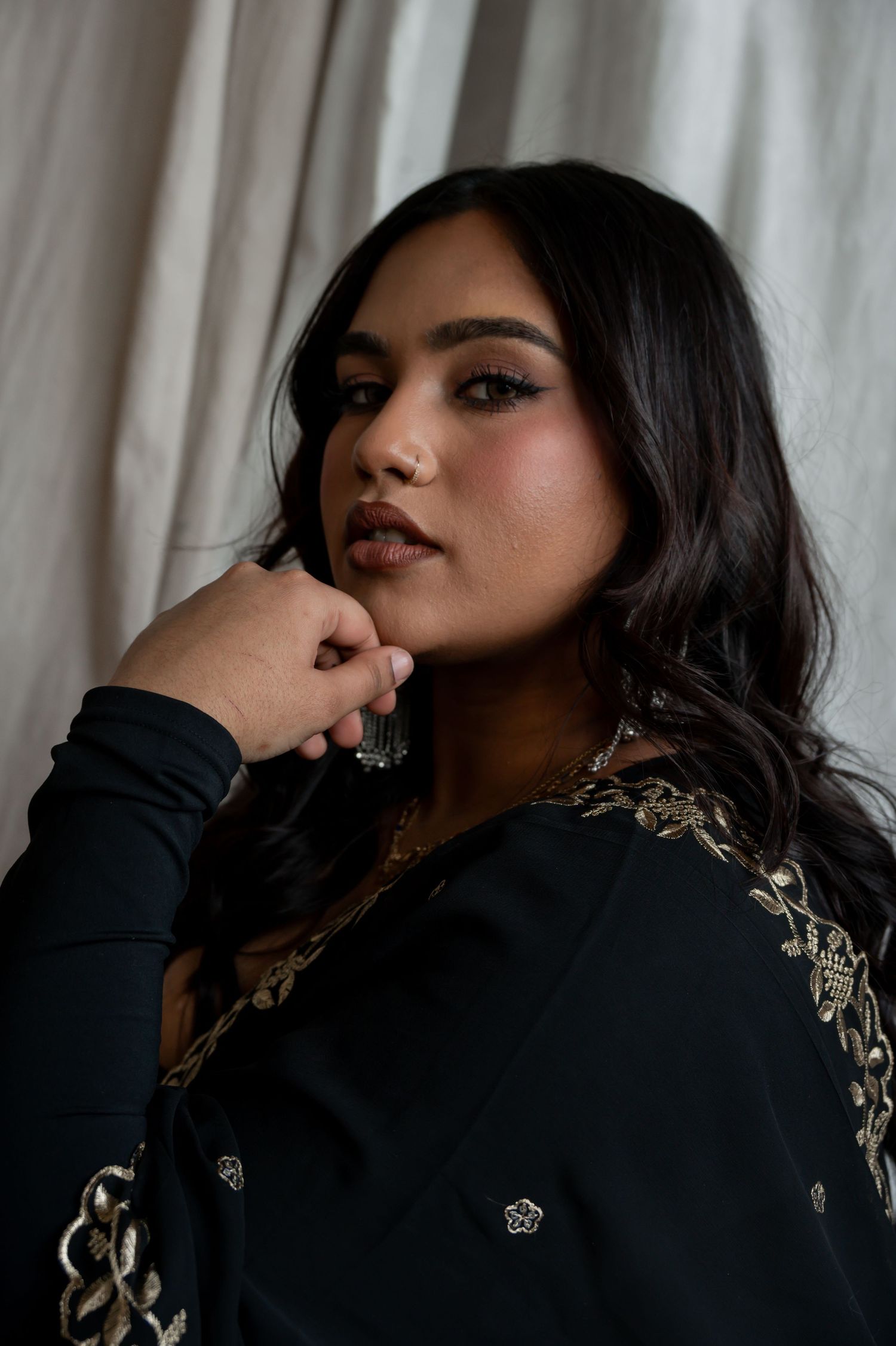 Close-up fashion series showcasing black dress with gold details in dramatic lighting.