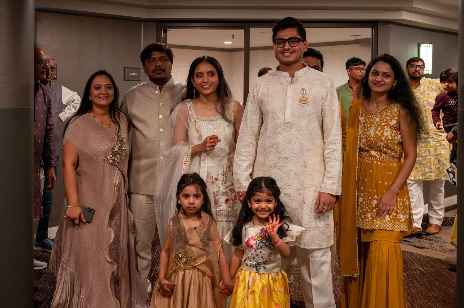 A group of people wearing traditional Indian formal attire pose together at a celebration event.