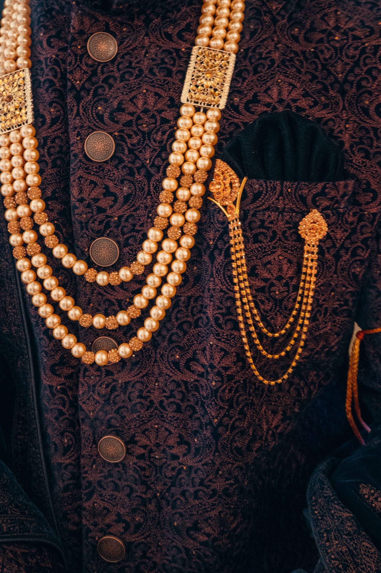 Traditional pearl necklaces with gold accents displayed against a dark patterned fabric background.