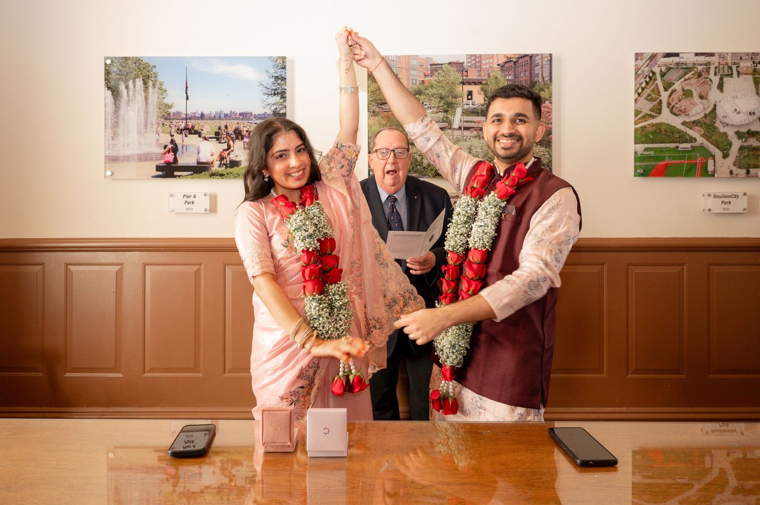 A couple in traditional South Asian wedding attire stands with an officiant during their civil ceremony.