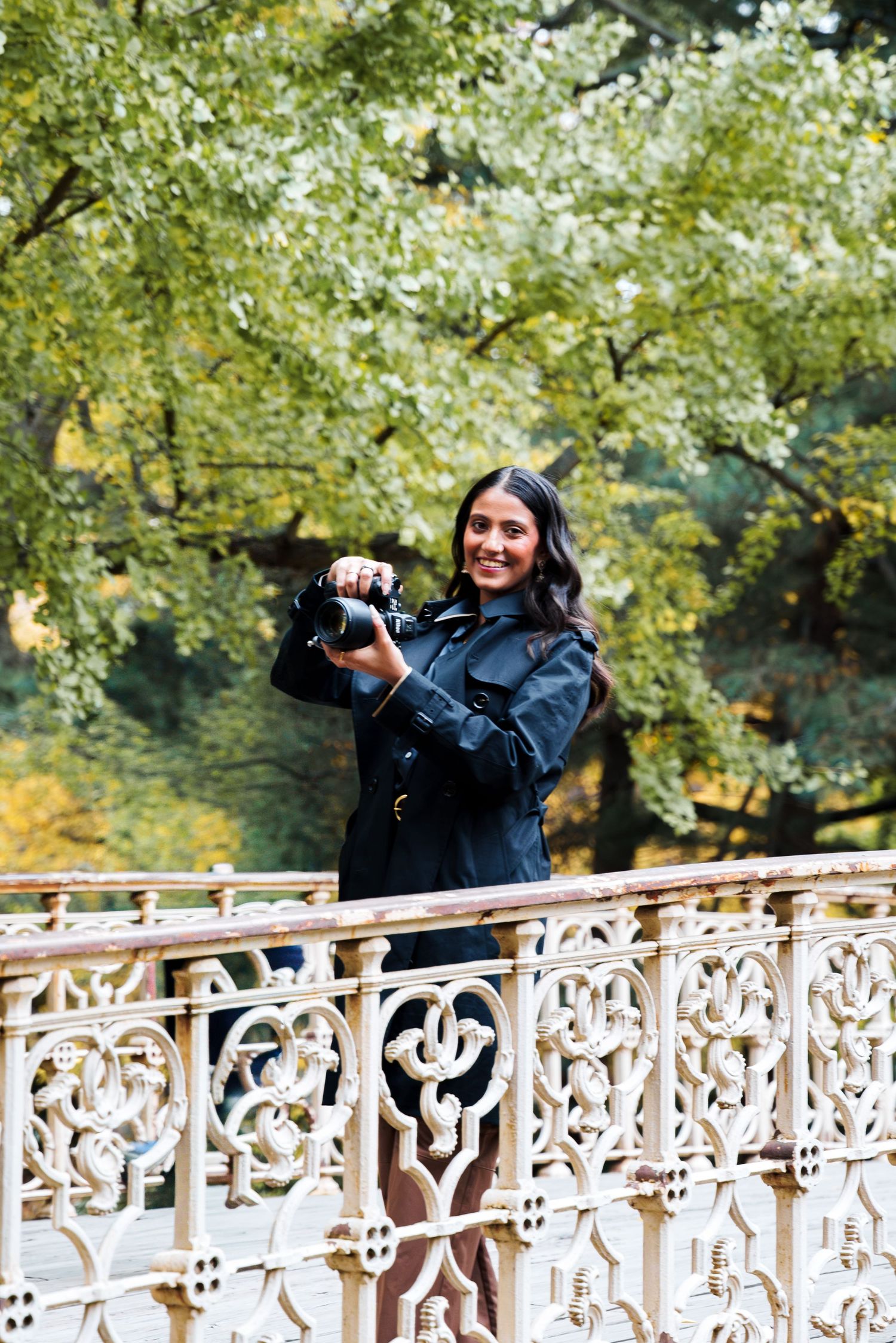 Professional photographer capturing moments on an ornate white bridge in a garden setting.