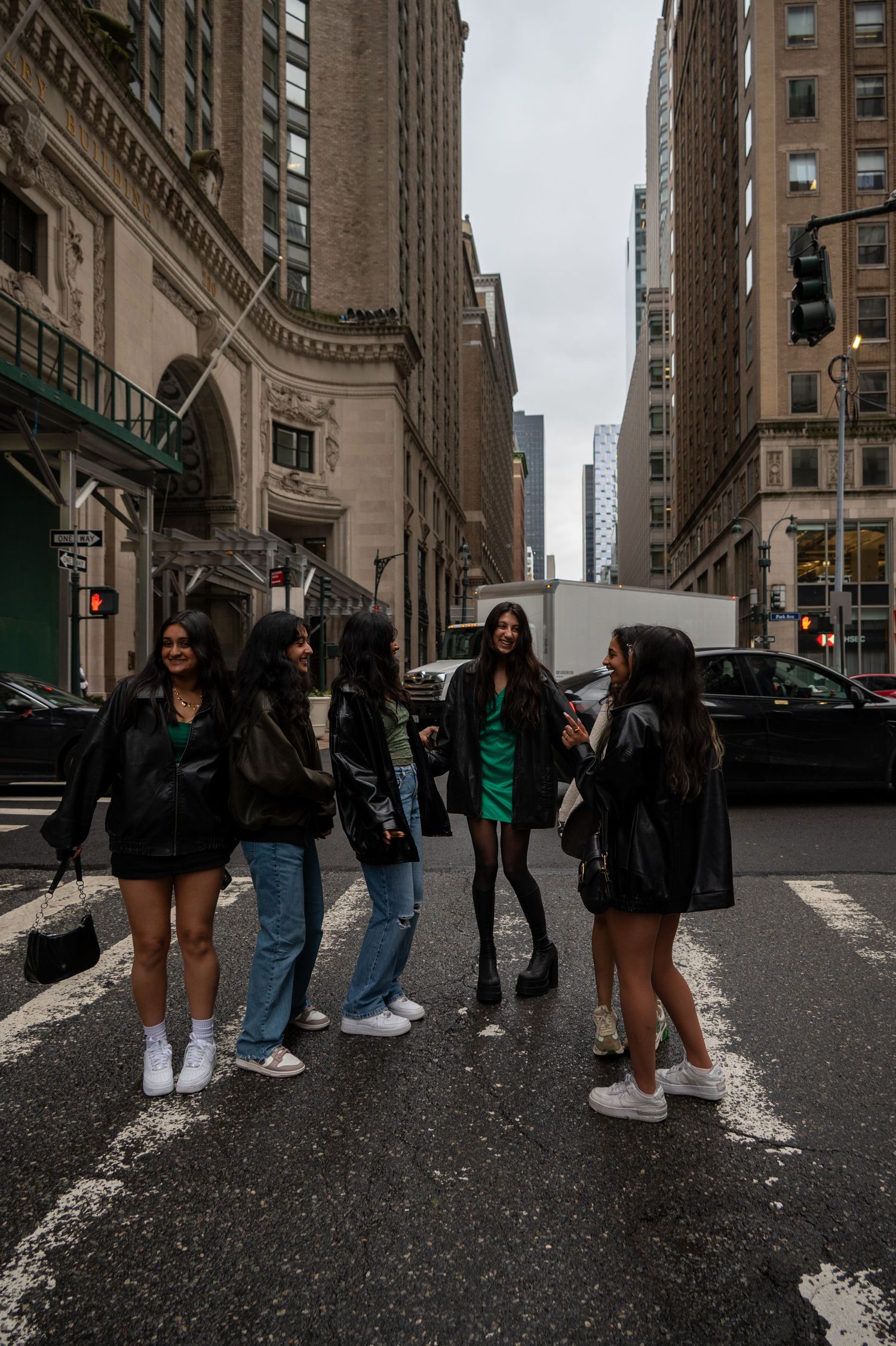 Group walking down urban street between tall buildings in New York City.