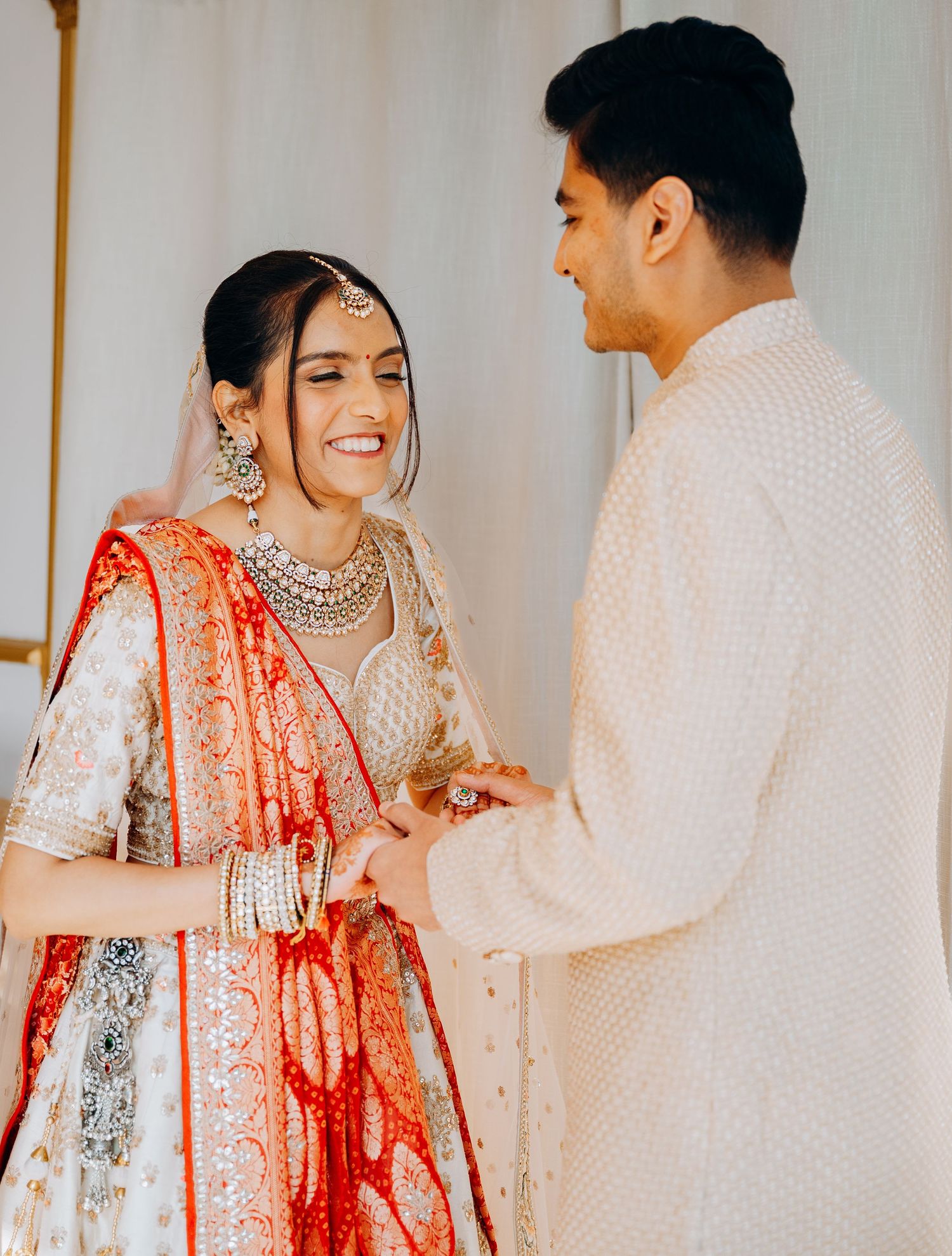A couple in traditional Indian wedding attire share joyful moments during their ceremony celebration.