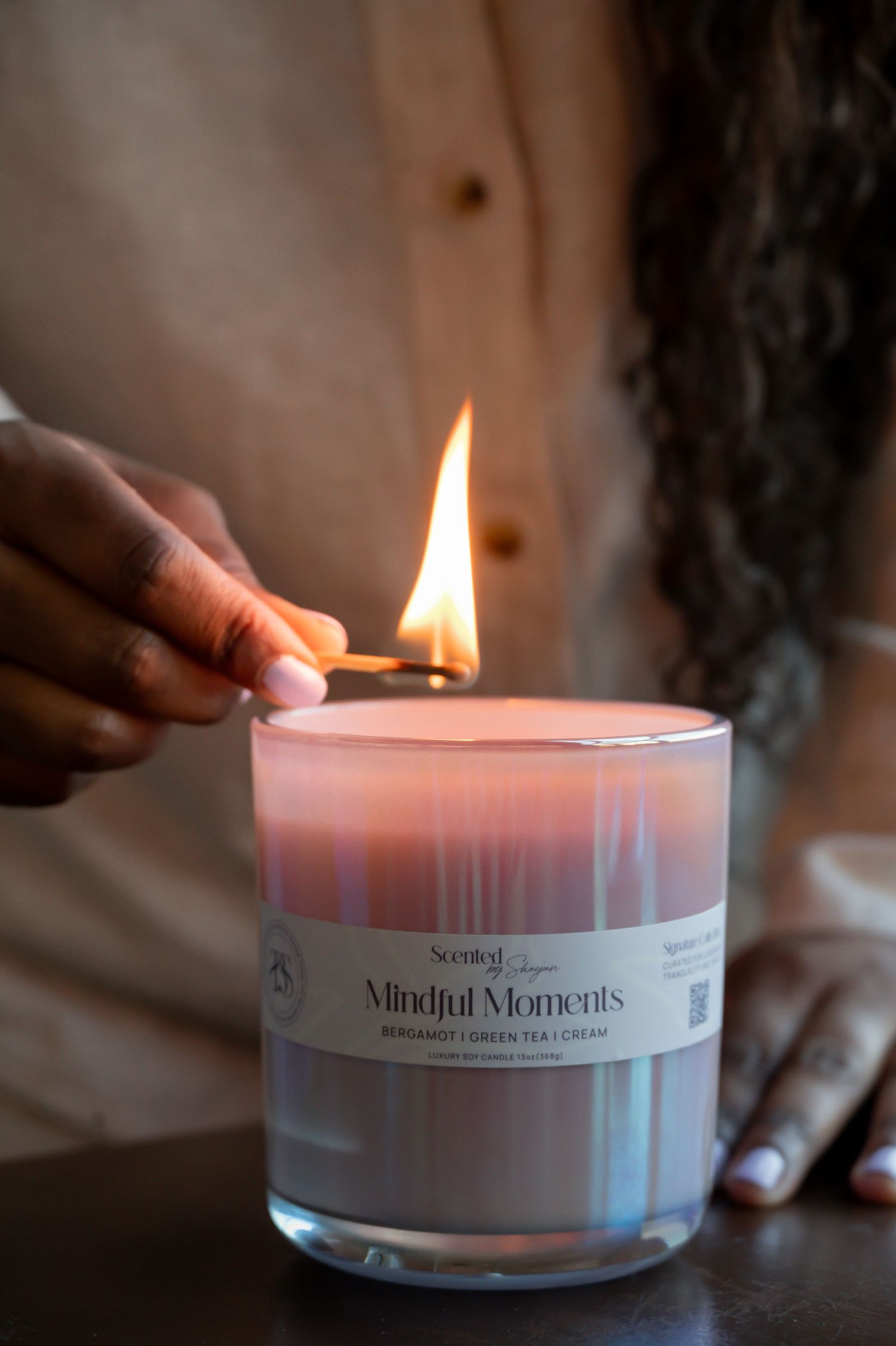 Hand lighting a white scented candle with gentle flame.