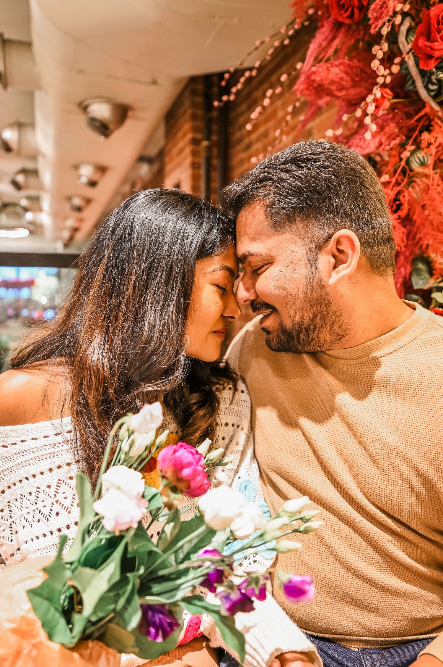 A romantic moment with flowers between a couple under red autumn decorations.