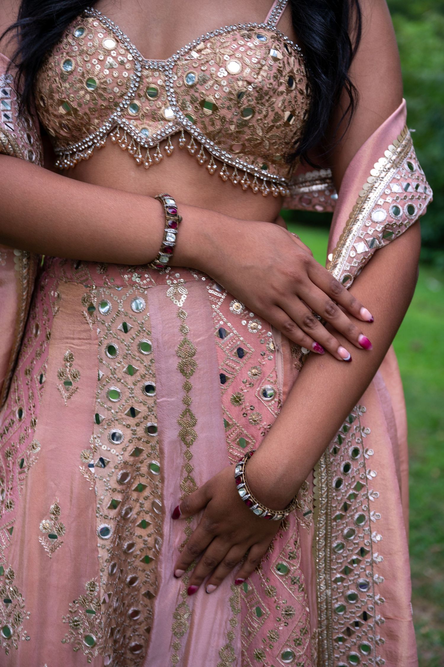 Close-up of pink and silver embellished dress fabric with intricate beadwork and crystal details.