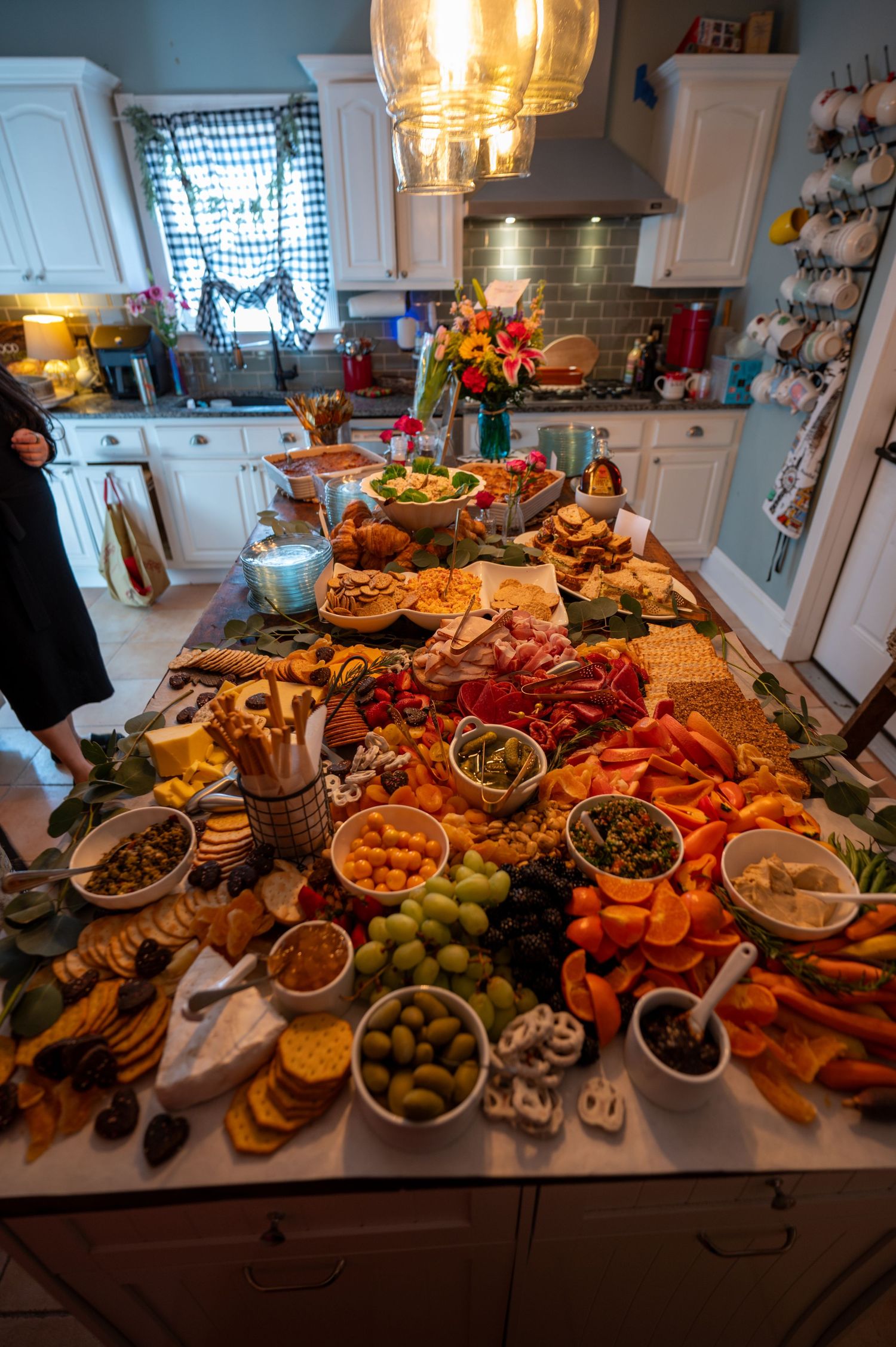 Elaborate charcuterie spread on kitchen island with meats, cheeses, fruits and appetizers.