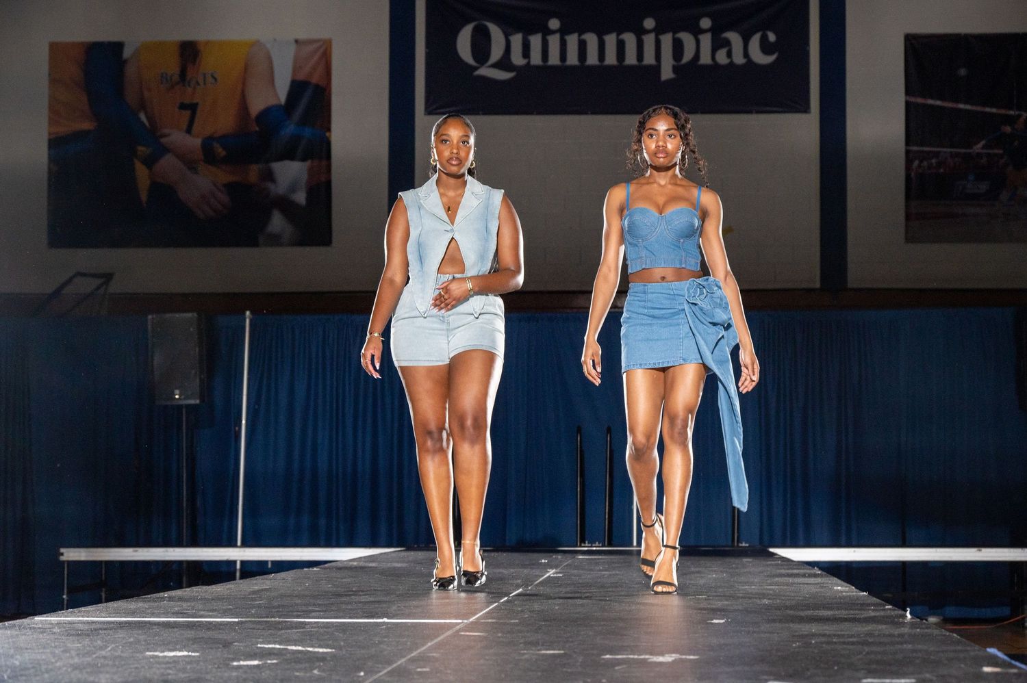 Dancers in blue costumes perform on stage at Quinnipiac University during a show.