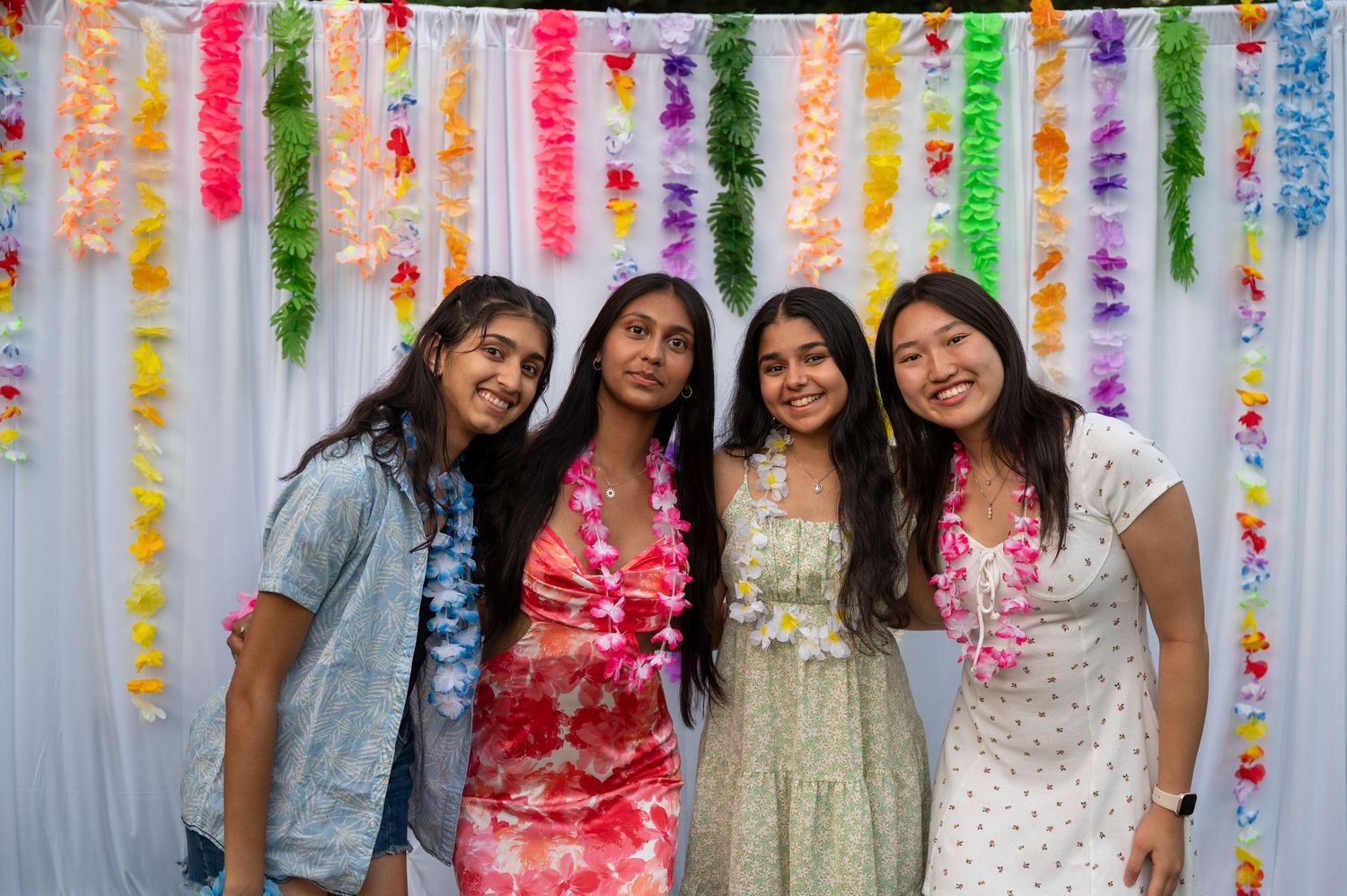 Festive group photo with friends in summer outfits against a backdrop of rainbow-colored streamers.
