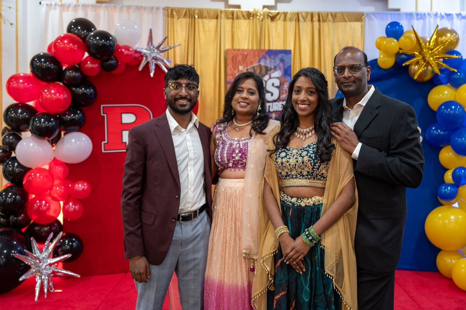 Graduation celebration with balloon decorations and guests posing for photos.