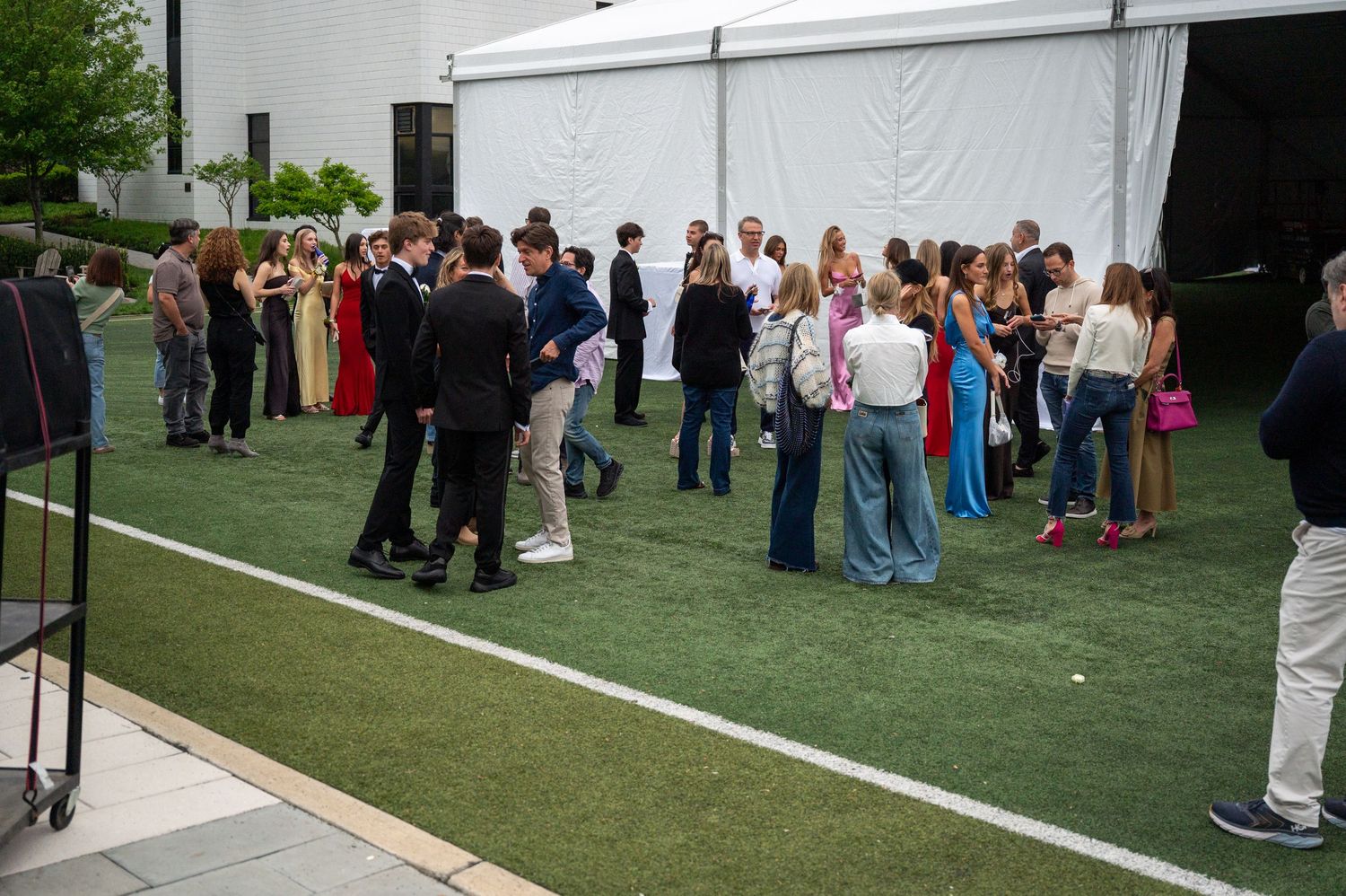 Large white event tents set up on a grassy lawn with people gathering outside.