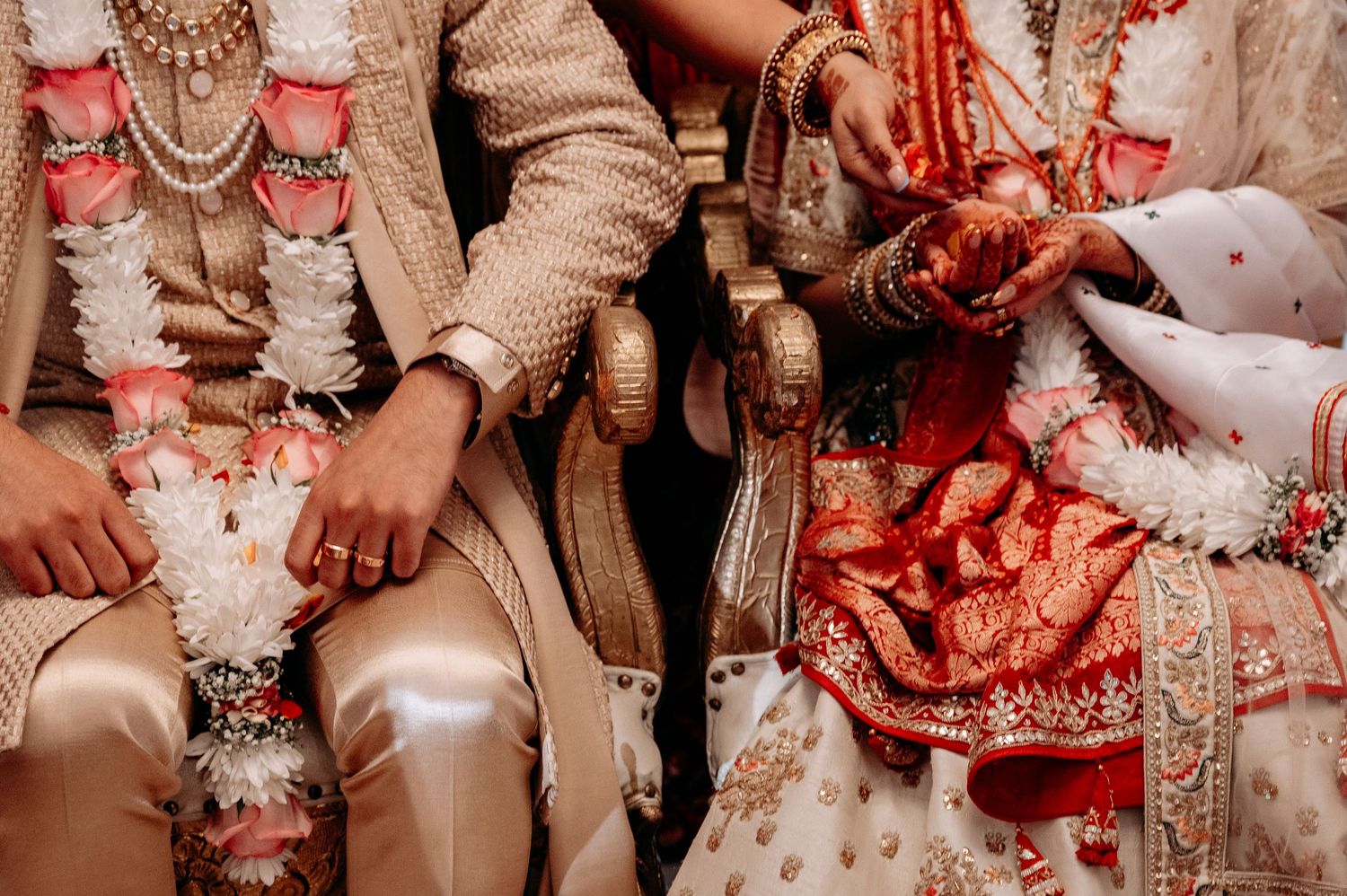 Close-up of traditional Indian wedding attire with intricate gold embroidery and jewelry.