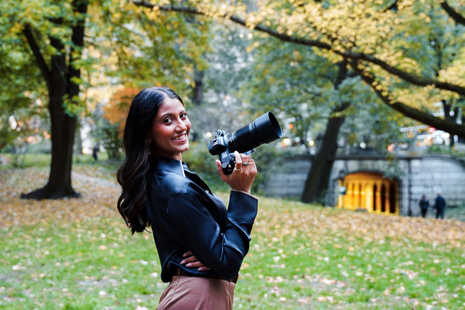 Joyful outdoor photoshoot in a park with fallen autumn leaves.