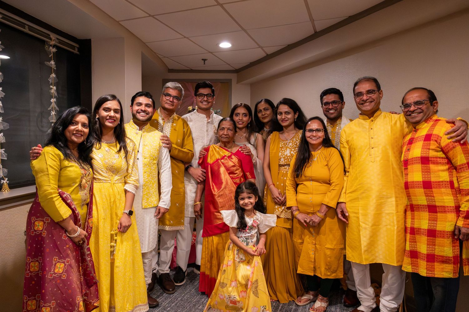 A group of people wearing vibrant yellow and orange traditional outfits pose together at a cultural celebration.