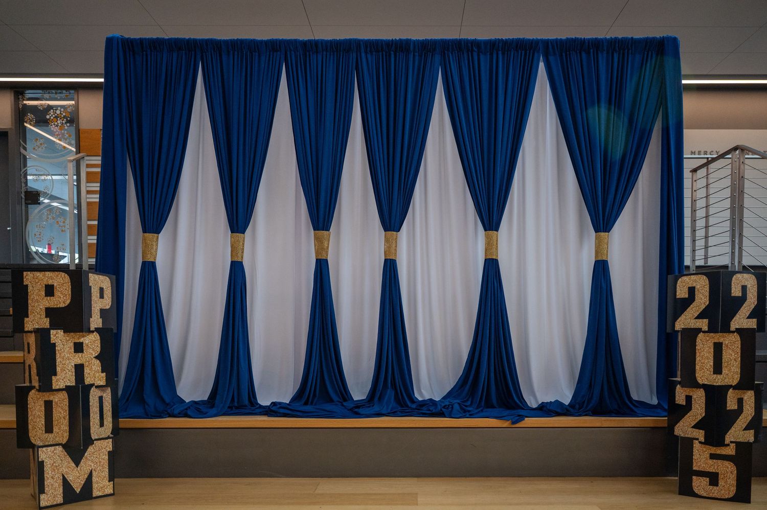 Blue and white draped curtain backdrop with decorative pattern.