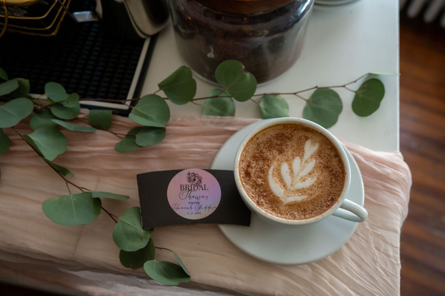 Artfully prepared lattes with latte art and eucalyptus leaves on a white surface.