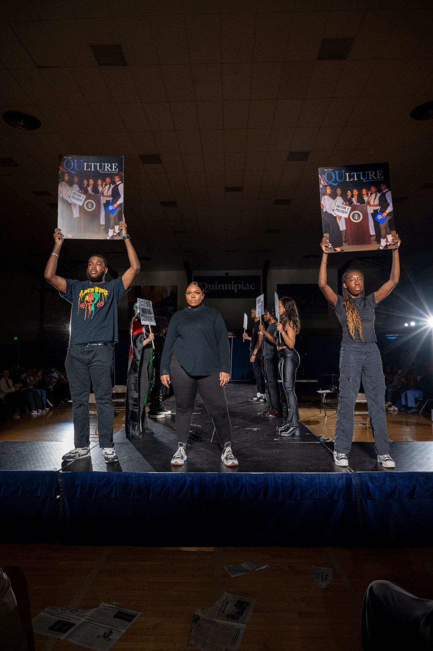 People holding up vinyl records during a dark performance on stage.
