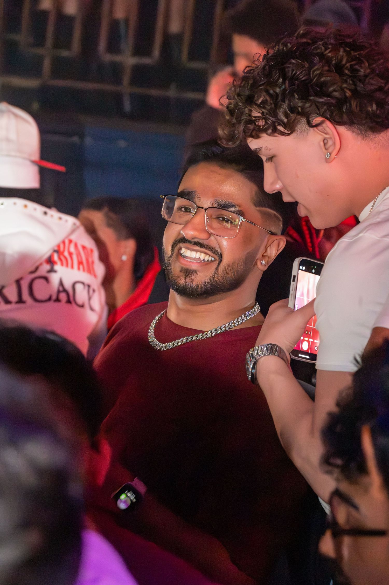 Crowd enjoying music at a nightclub under red and purple lighting.