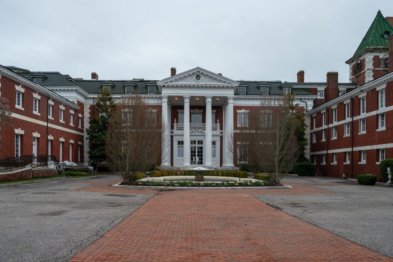 Panoramic view of a red brick colonial style building complex with white columns and walkways.