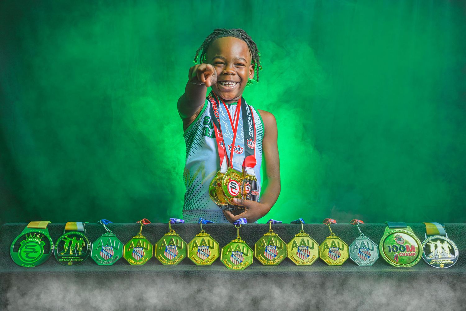 A row of gold medals displayed on a green background with a young athlete proudly showing off their achievements.
