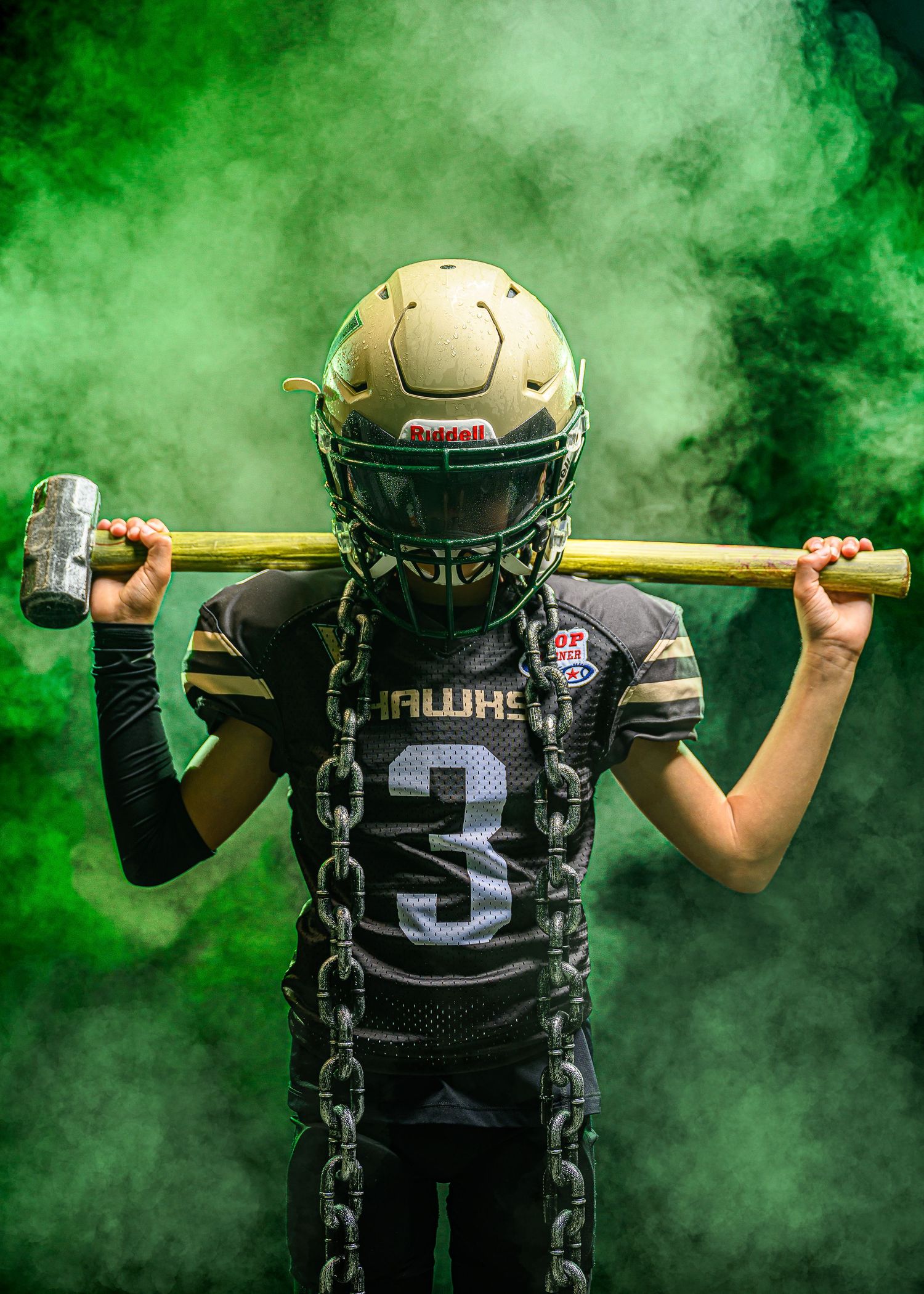 Football player holding a baseball bat in dramatic green smoke effect, shot from behind with jersey number 15 visible.