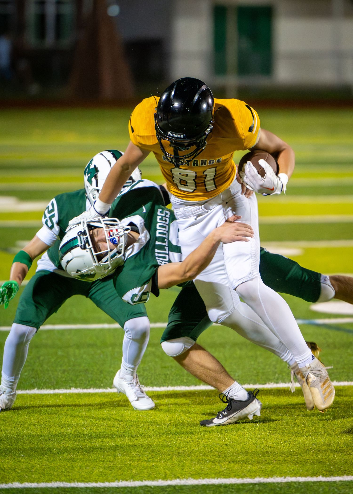 Series of football players diving and lunging to make tackles on the playing field in green and yellow uniforms.