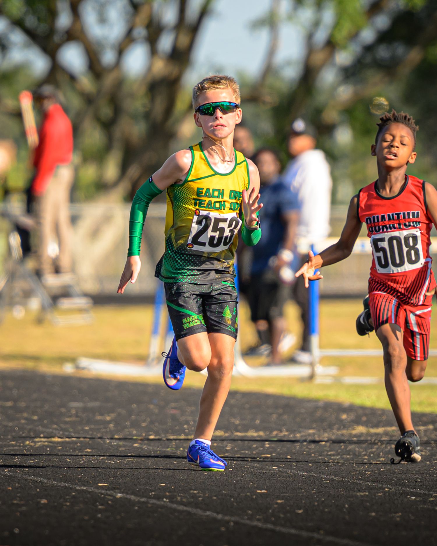 Two youth athletes sprinting on a track during a competitive race.