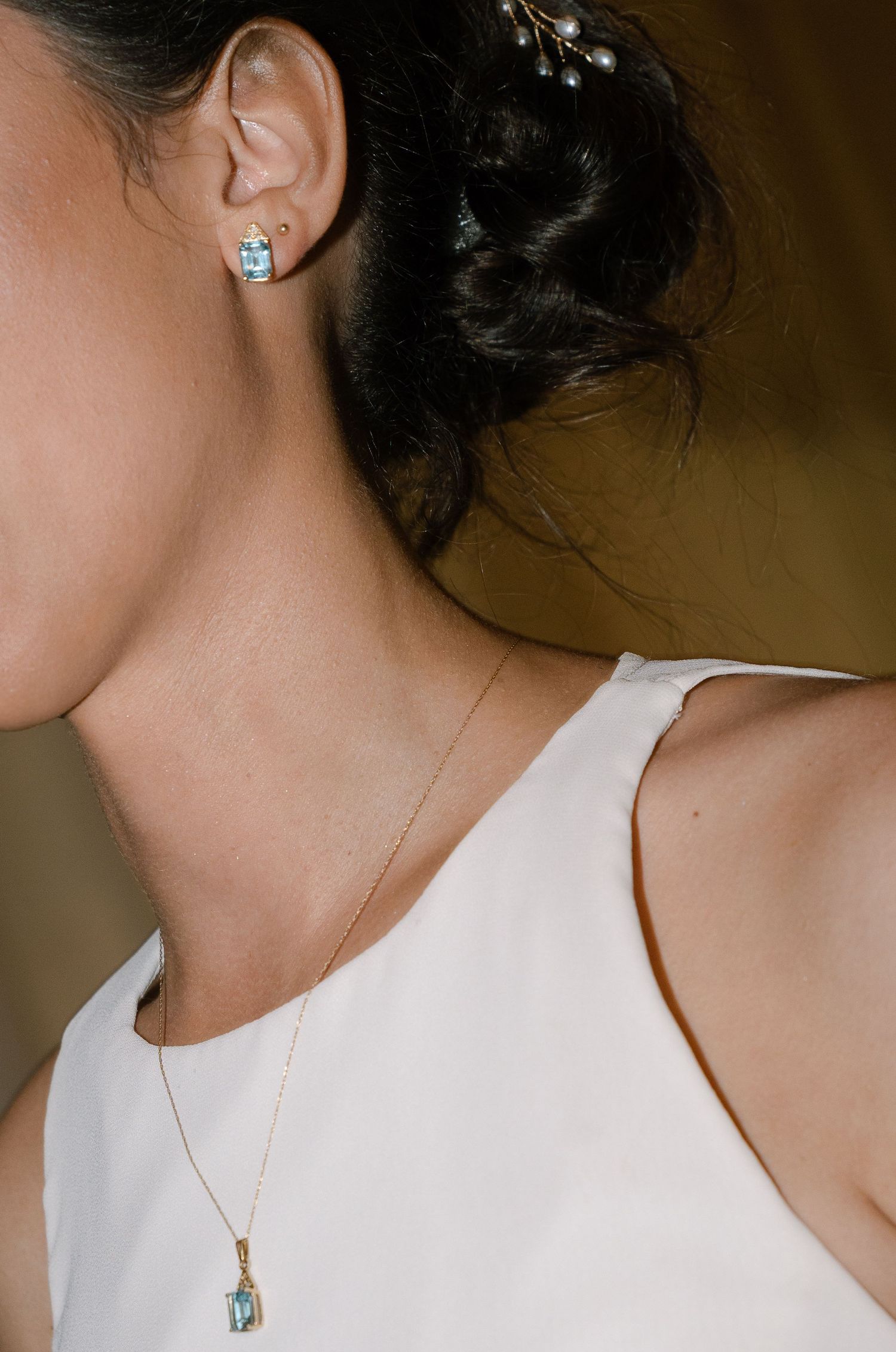 Close-up view of delicate jewelry and neckline details on elegant white clothing.