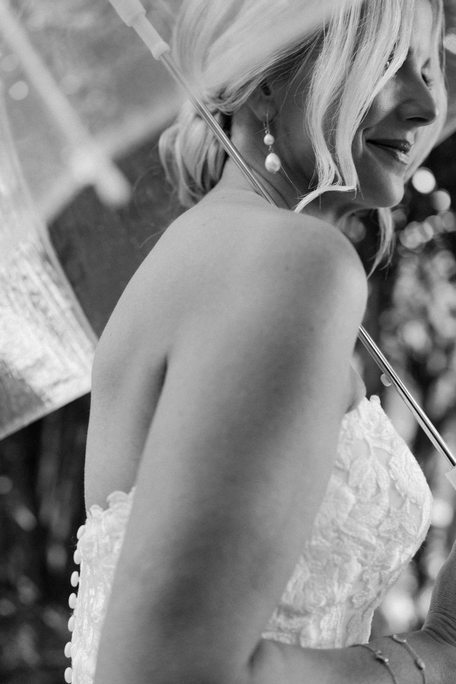 Close-up details of a white lace wedding dress back against a dark background.