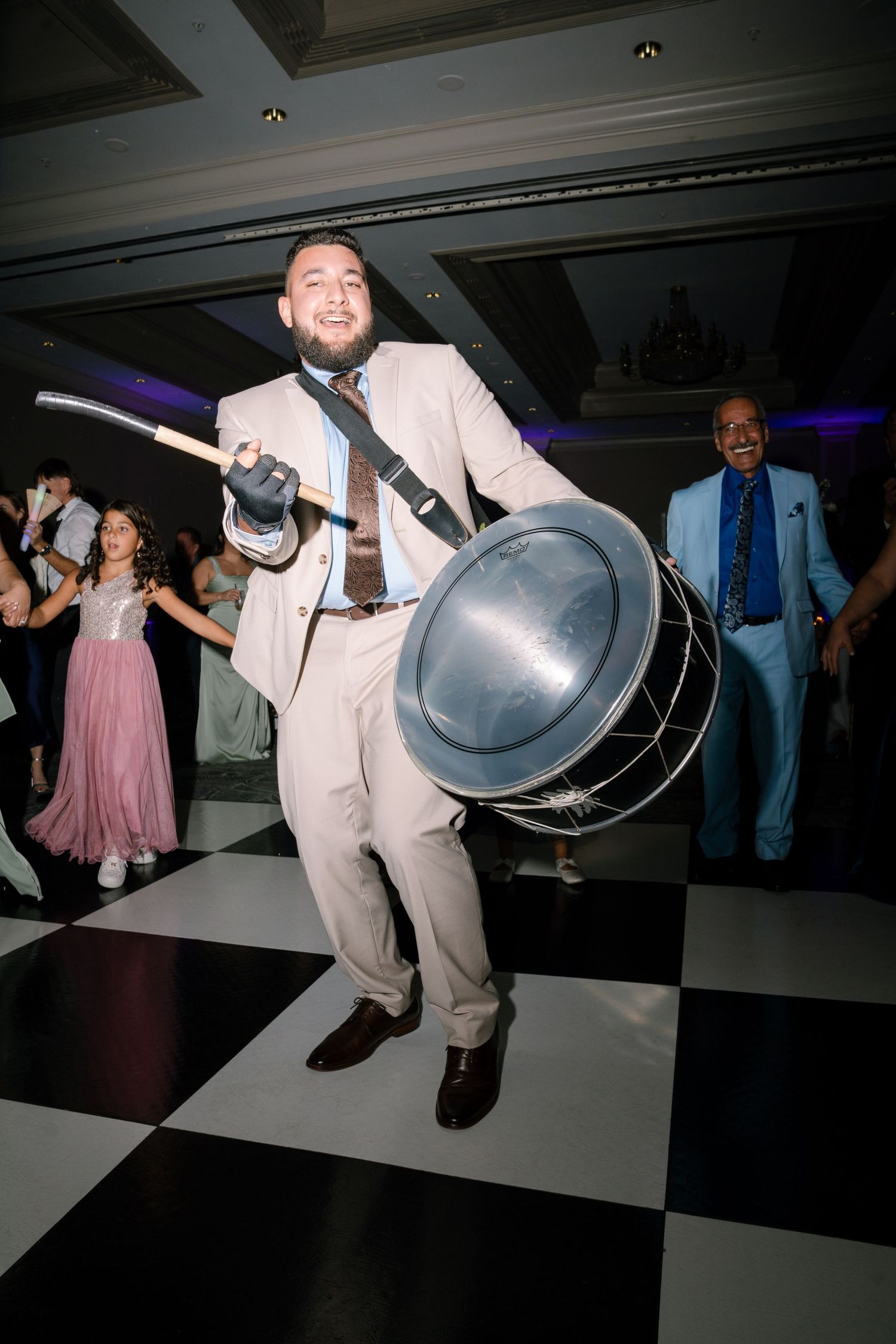 Wedding reception guests dancing on a black and white checkered dance floor with decorative lighting.