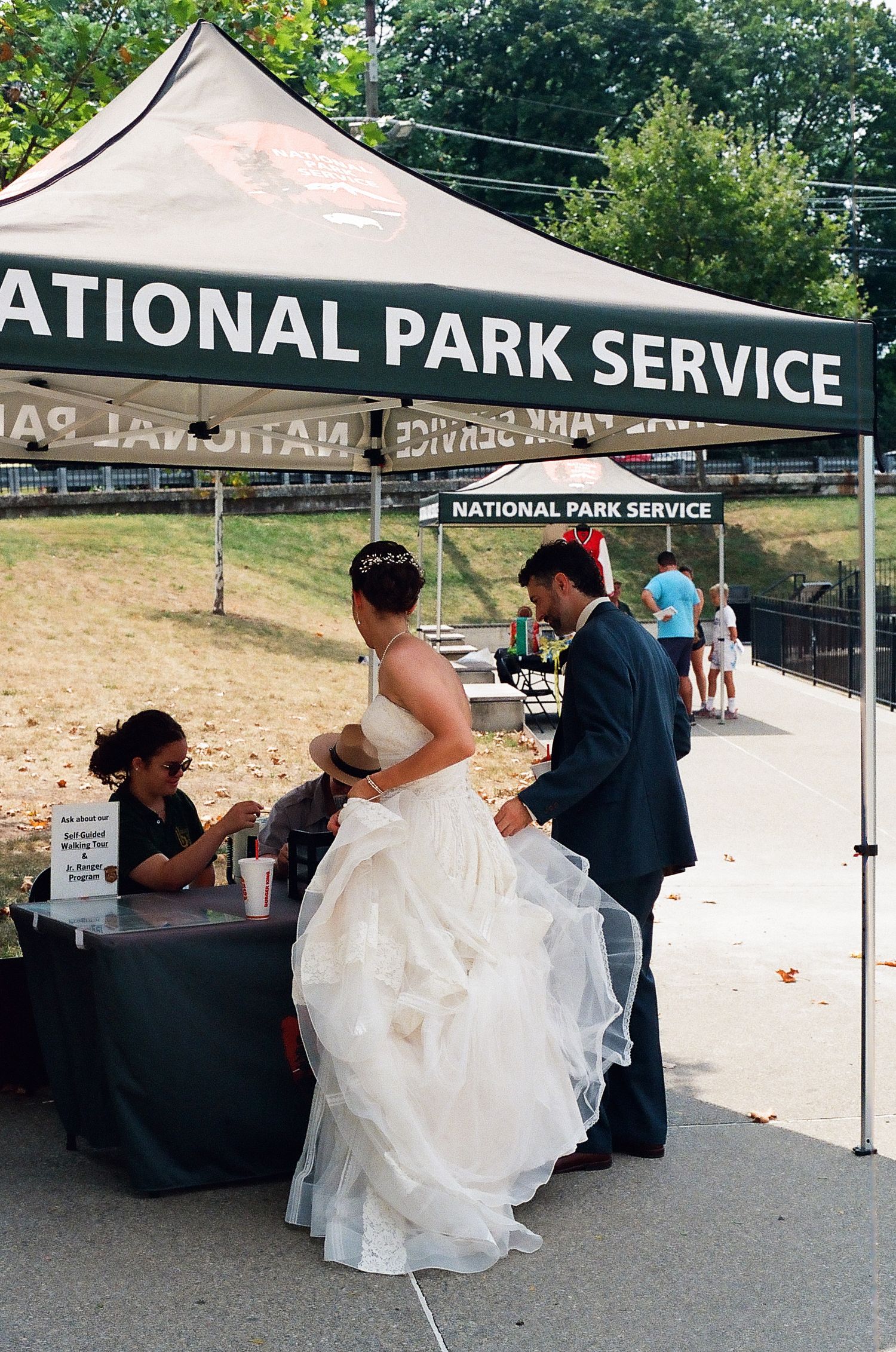 Wedding party gathered under a National Park Service tent during an outdoor ceremony.