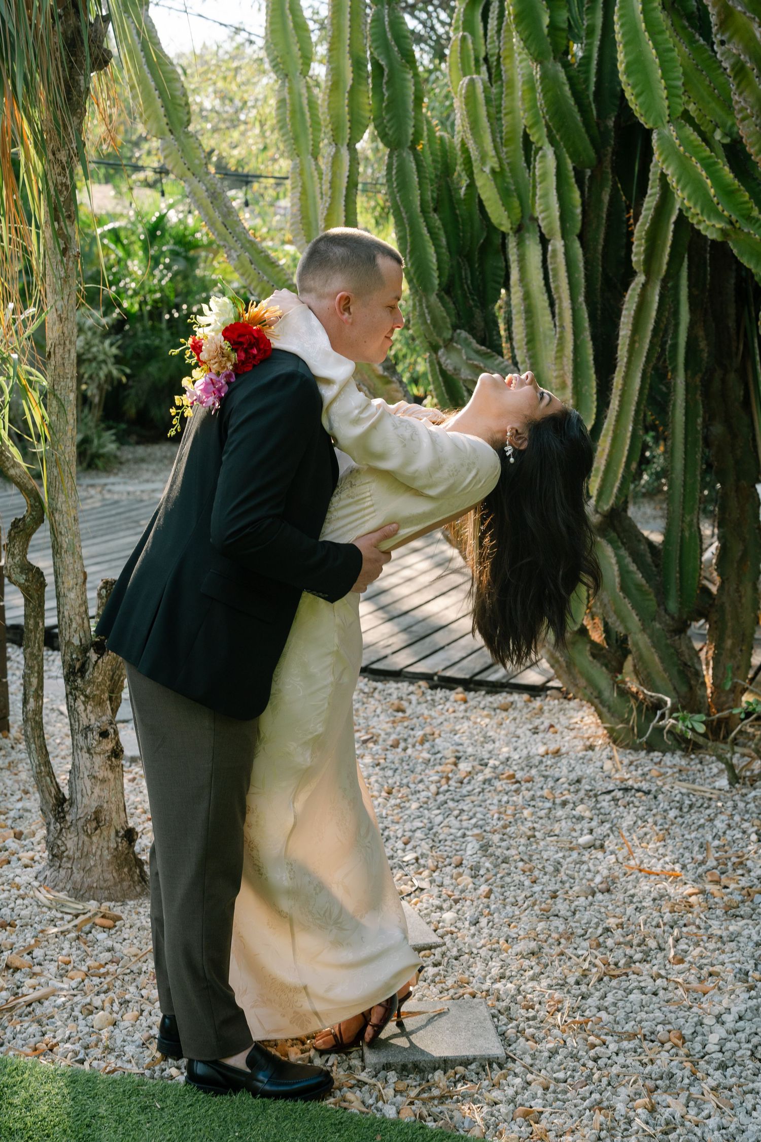Romantic moment captured between couple in tropical garden with cactus backdrop.