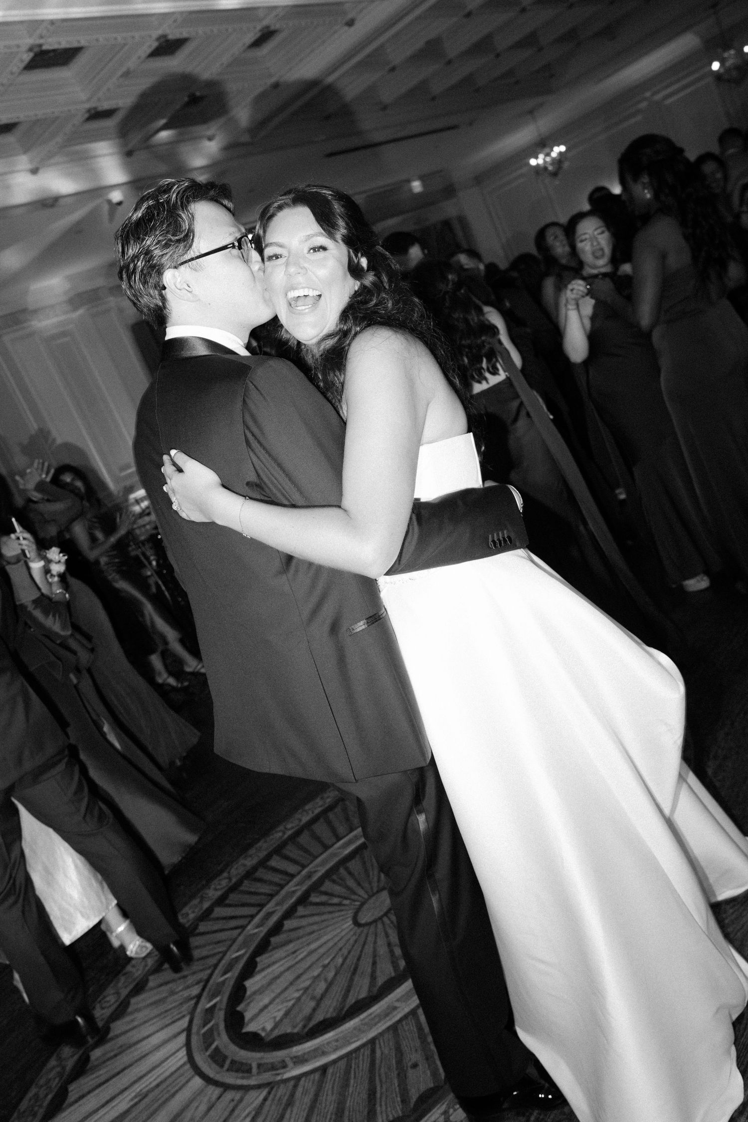 Wedding reception dance floor with guests celebrating in black and white photography.