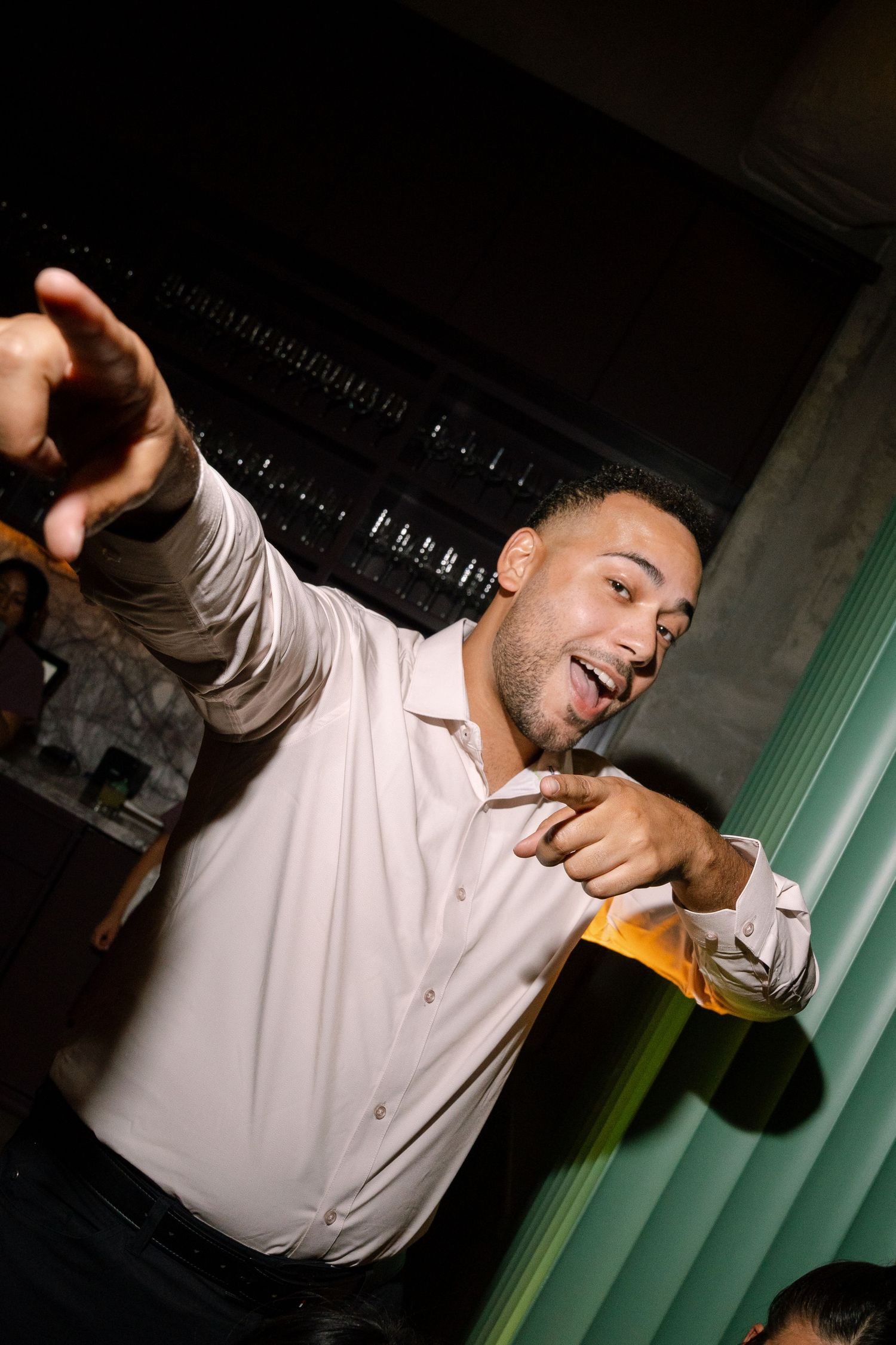 Energetic party guest dancing and celebrating in front of mint green curtains.