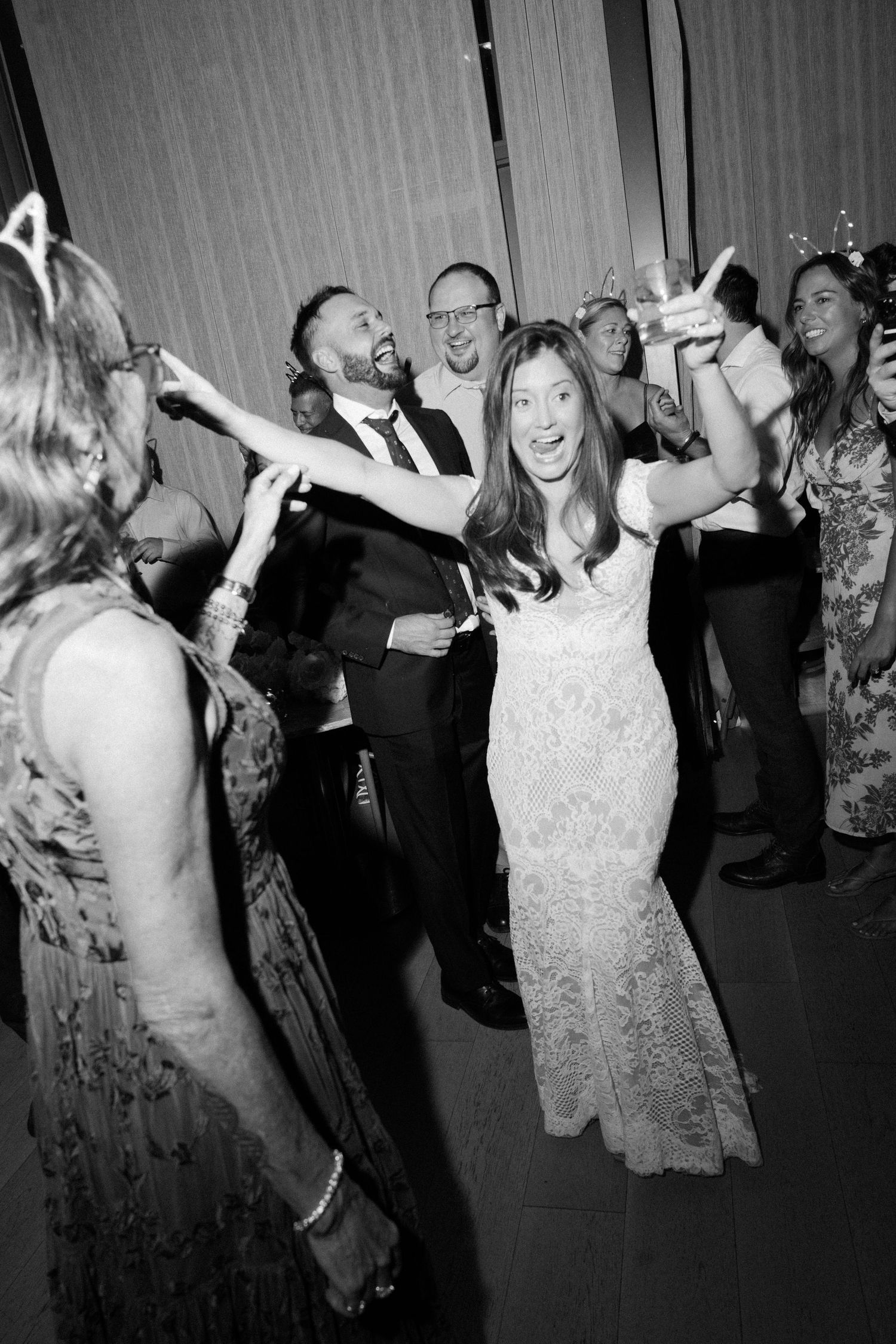 Black and white photo sequence of wedding guests dancing and celebrating on a dimly lit dance floor.